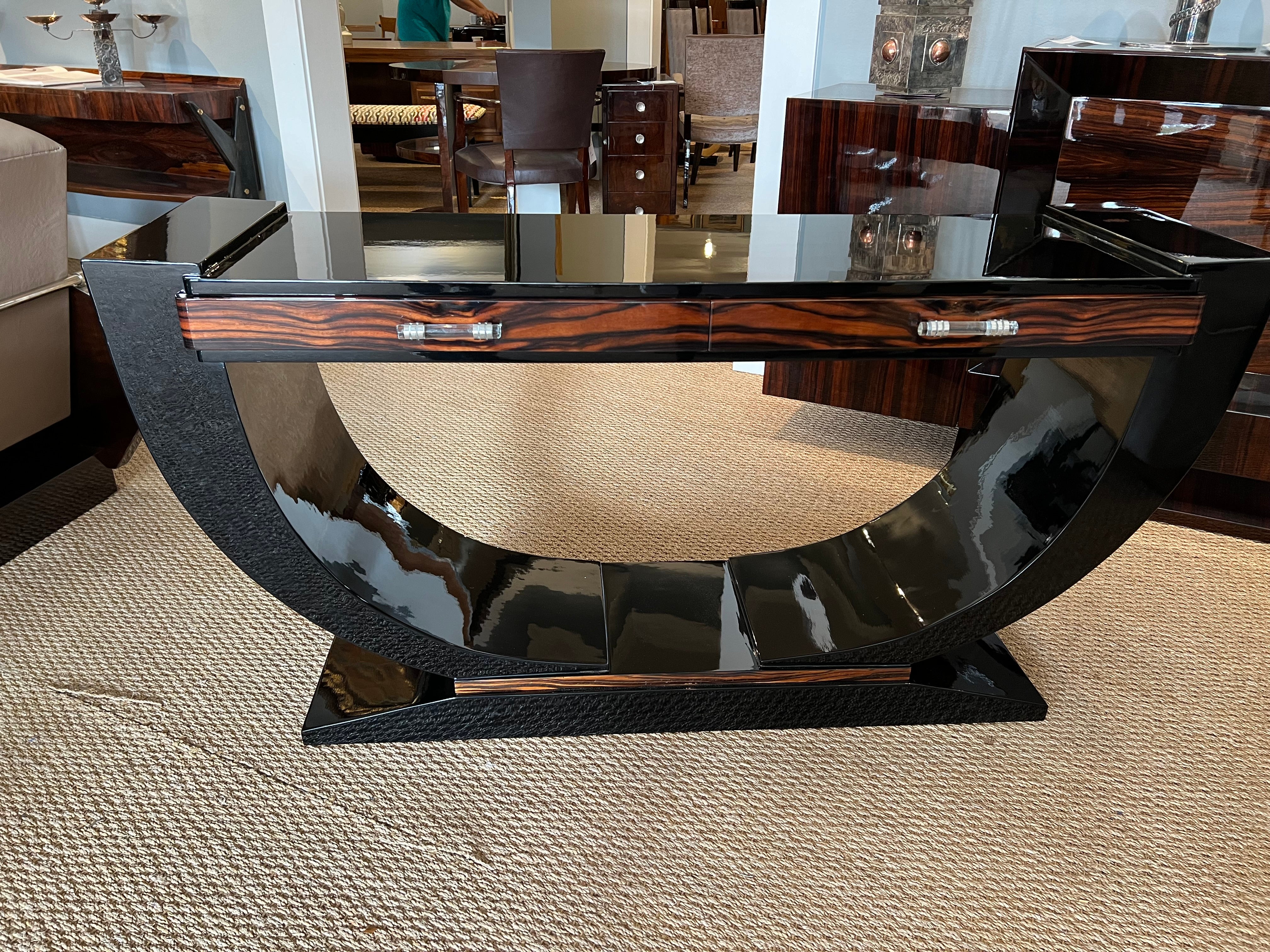 Gorgeous Art Deco French console made out Macassar wood and ebony. There is skillful juxtaposition between wood colors. Console top is supported by 2 semi-circular legs that are attached to the trapezoid prominent base. Top has 2 drawers with