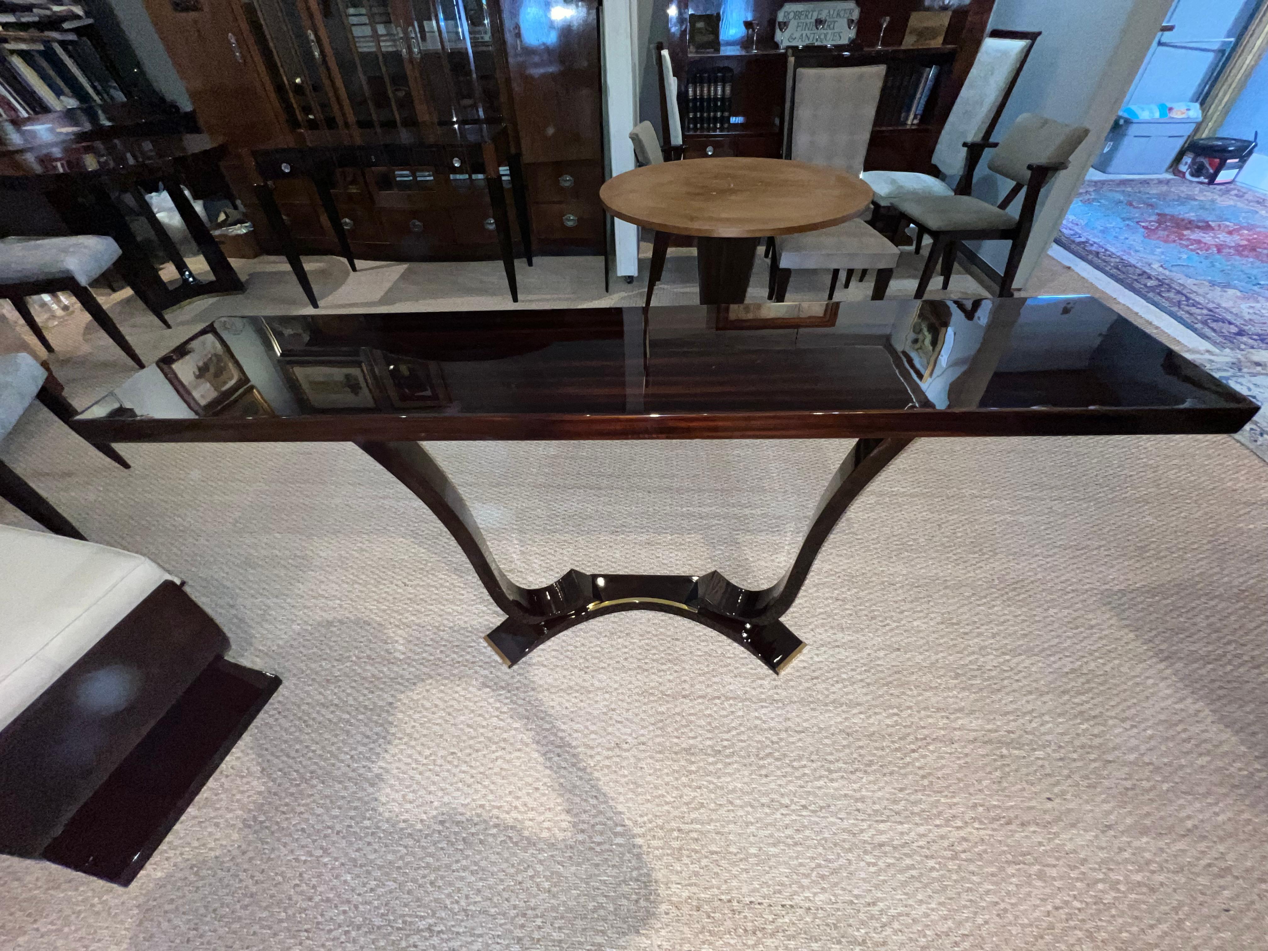 Console’s top is elevated by slightly curved legs on each side. Legs are attached to the “horse shoe” shape base, middle part and sides of which are decorated with brass decorative elements. 

Condition is perfect. Restored. 

 Measures: 59” x 12.5”