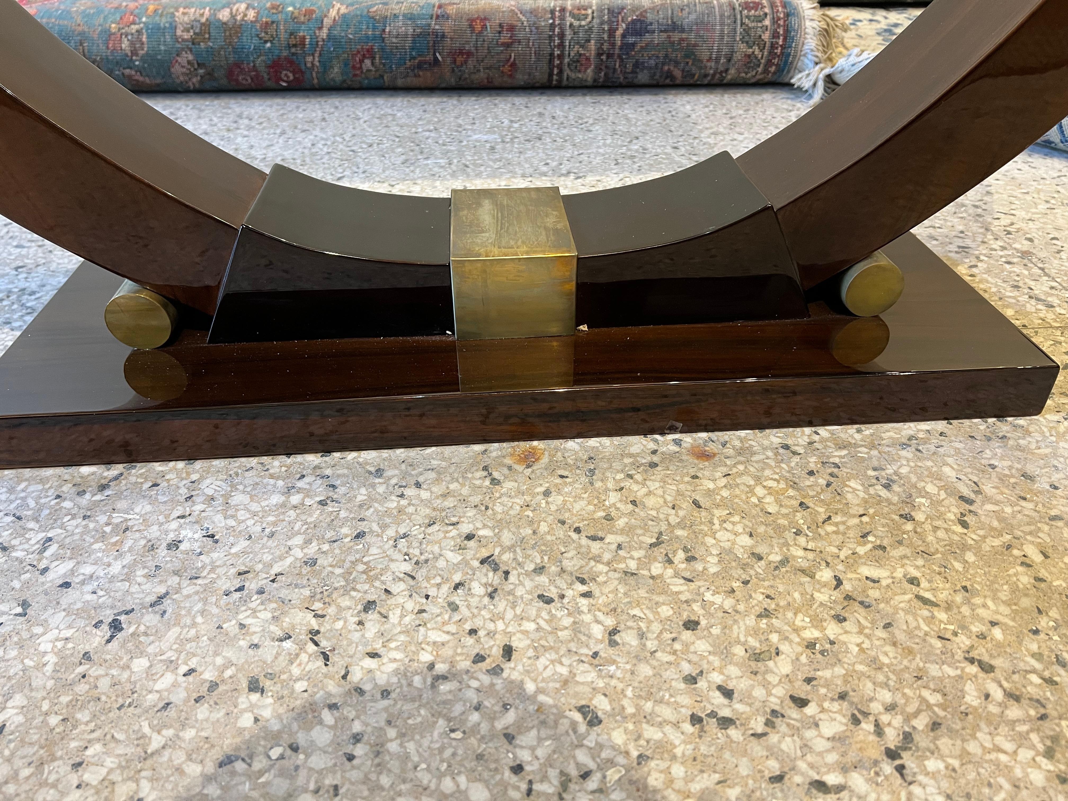 Beautiful Art Deco period console made out of walnut wood. Wood grain is visible on the top. Bottom of the console top wrapped with brass ribbon. Supported by semi-curved leg that is attached to the trapezoid shape base with brass decorative