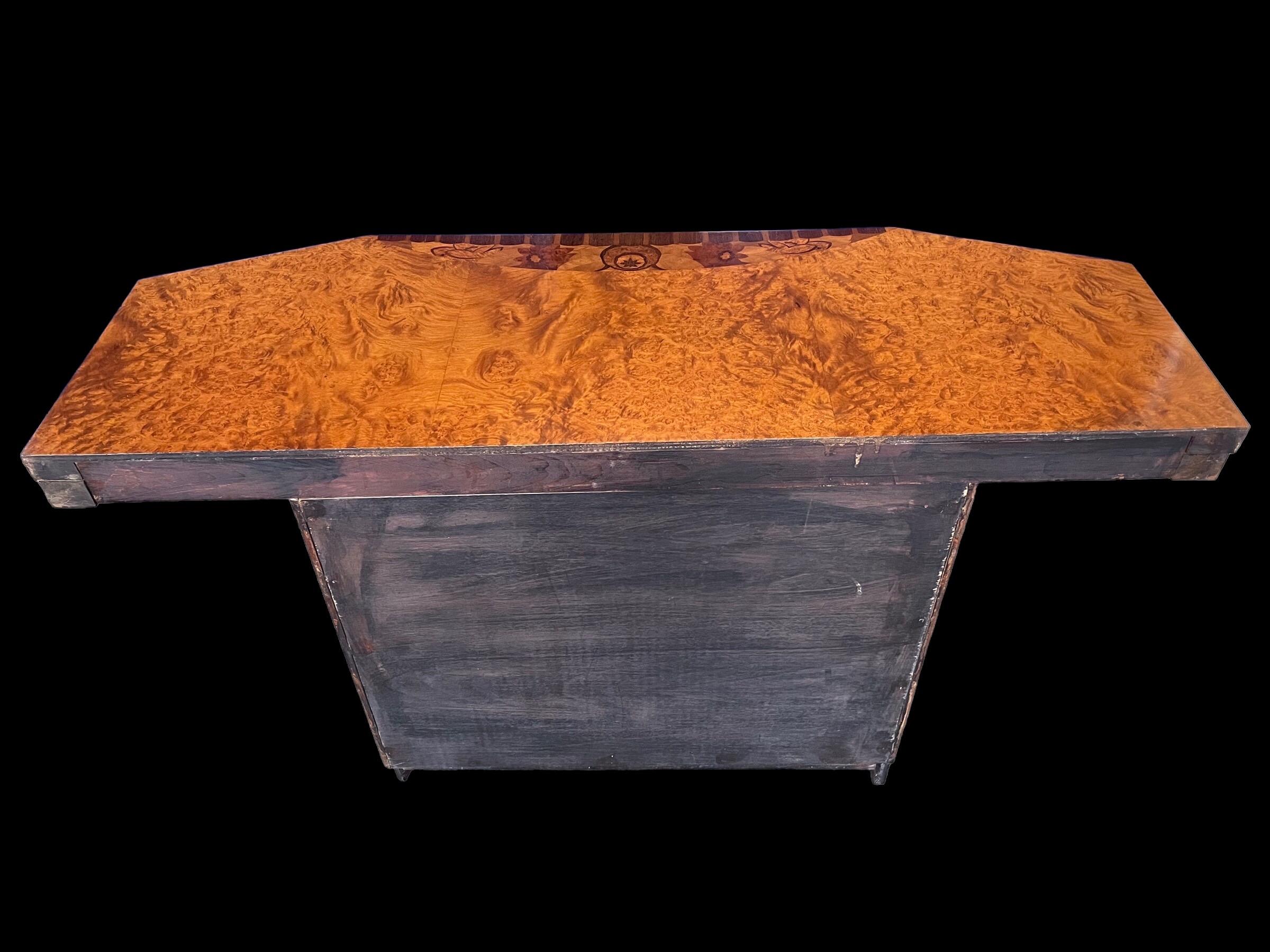 Superb Art Deco French Console Table with quality floral and foliage marquetry detailing to front of the top and to the base of the pedestal. The top with slanted front sides and the base curved to the front, with a scalloped black plinth.
 
All our