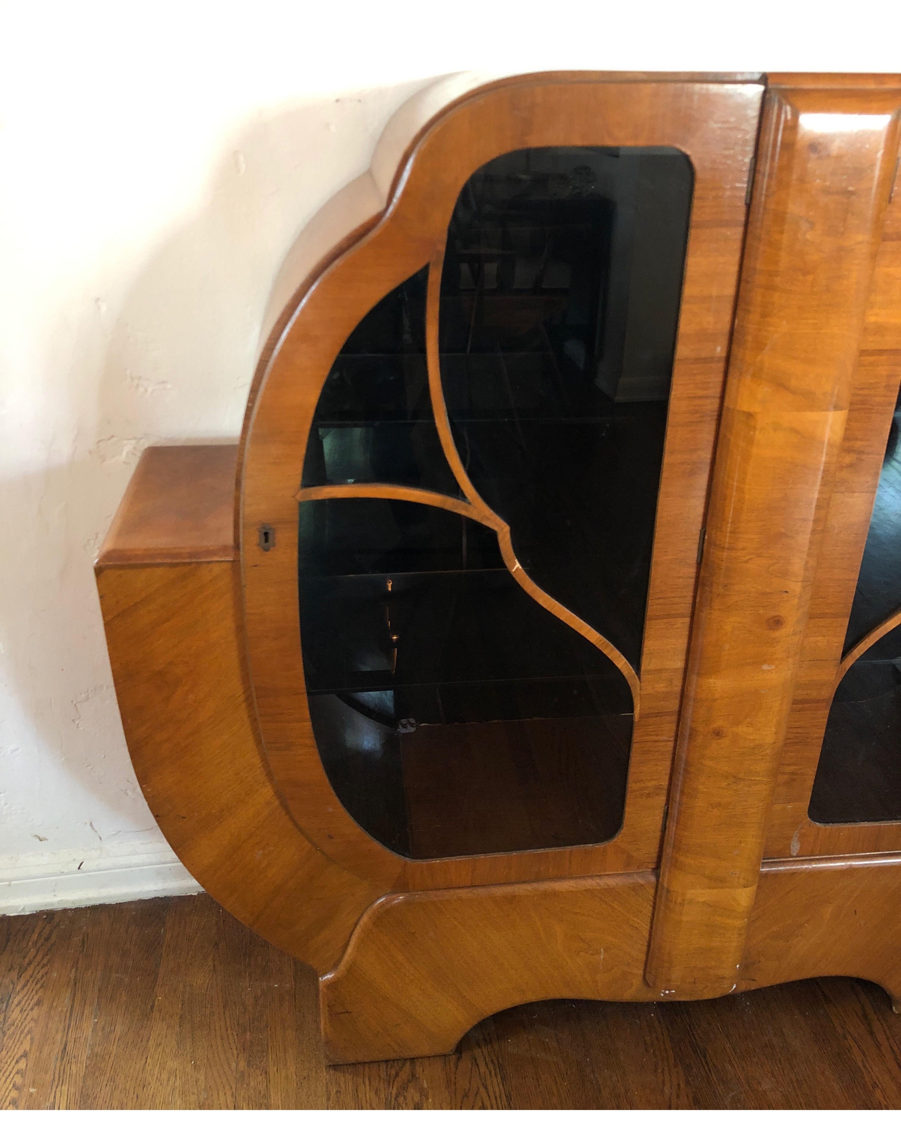 Art Deco dry bar in walnut with glass doors. Two glass shelves inside. 
Back is a black fiberglass with a crack that was repaired. 

Overall good condition with minor wear consistent with age.