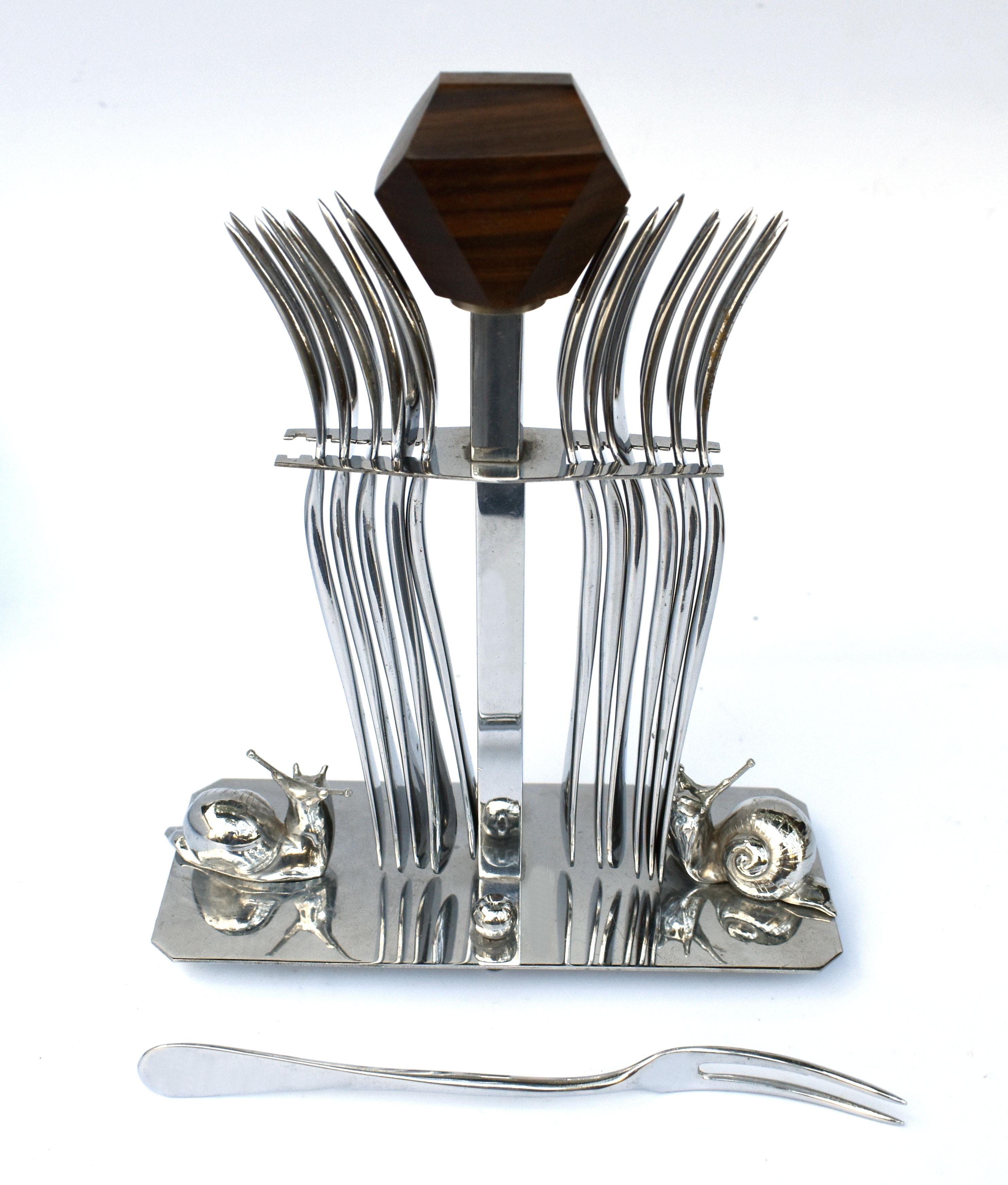 Very much in the style of Jacque Adnet is this wonderful 1930's Art Deco fork set originating from France . A simple chrome frame holds two chrome snails and central pole with exotic palisander handle, part of the Rosewood family with 12 chrome