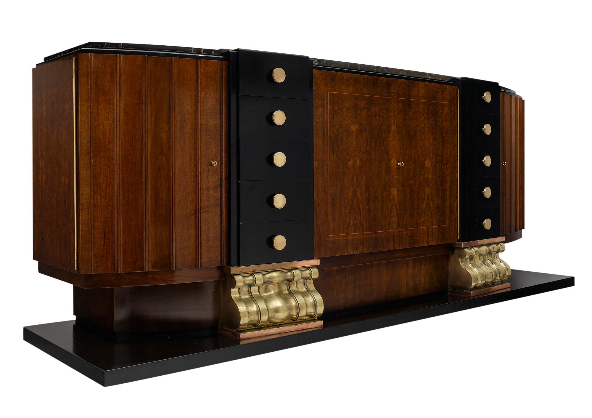 Art Deco buffet from France made of burled walnut and ebonized walnut featuring ample adjustable storage behind four doors. There are ten dovetailed drawers with original bronze hardware. The platform base is enhanced with two important brass feet.