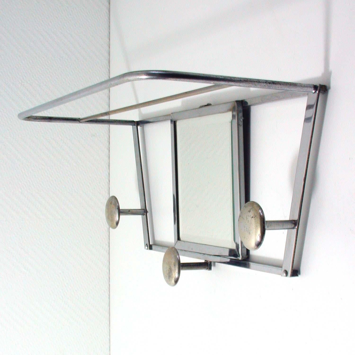 This Industrial style vintage coat rack was manufactured in France in the 1930s. It is made of chrome and has got three hooks and a mirror.
