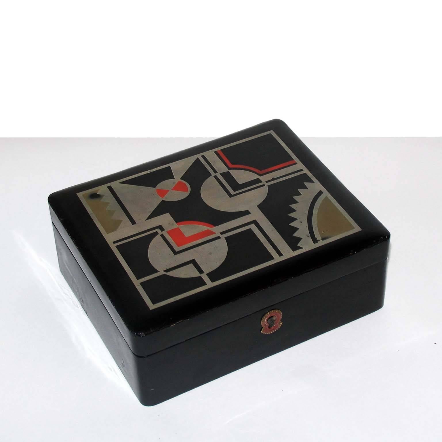 Art Deco French lacquered box, jewelry box, geometric decor, in the style for Jean Dunand.
Decorative or jewelry Art Deco box, France, circa 1930. Black lacquered, lid decorated with geometric design in silver leaf, light red and beige lacquer.