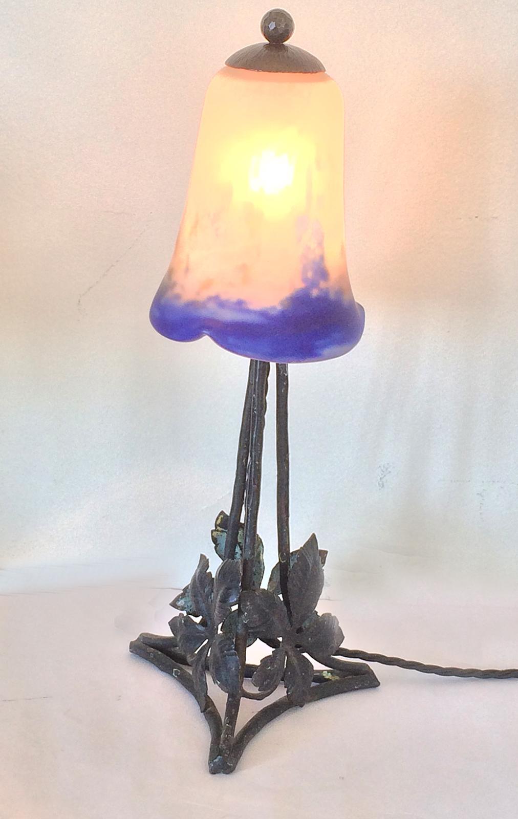 Art Deco French lamp, hand-forged iron with three sides and maple leaf details. Added detail to the iron, Penne hammered finial and top cap of iron. Glass shade “Tulip” with 3 upturned edges in blue and white with touches of orange, by Degue France.