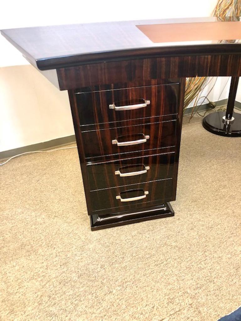 The top of the desk has curvilinear shape. It attached to the spacious drawers on both sides. On the right here is one big drawer with a small round handle, on the left there is four wide drawers with elongated curved chrome handles. Underneath of