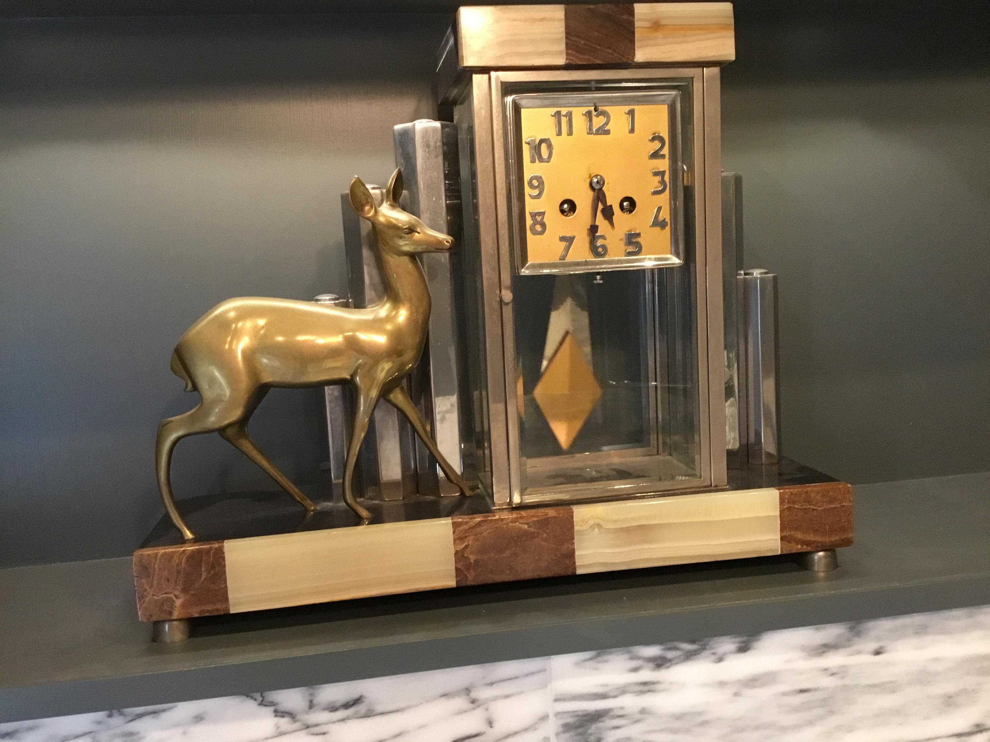 A very attractive Art Deco mantel clock, made from cream and beige marble, chrome and brass.
The clock has two-chrome columns to one side of the clock face and three graduated chrome columns and a deer to the other side.
A brass clock face and