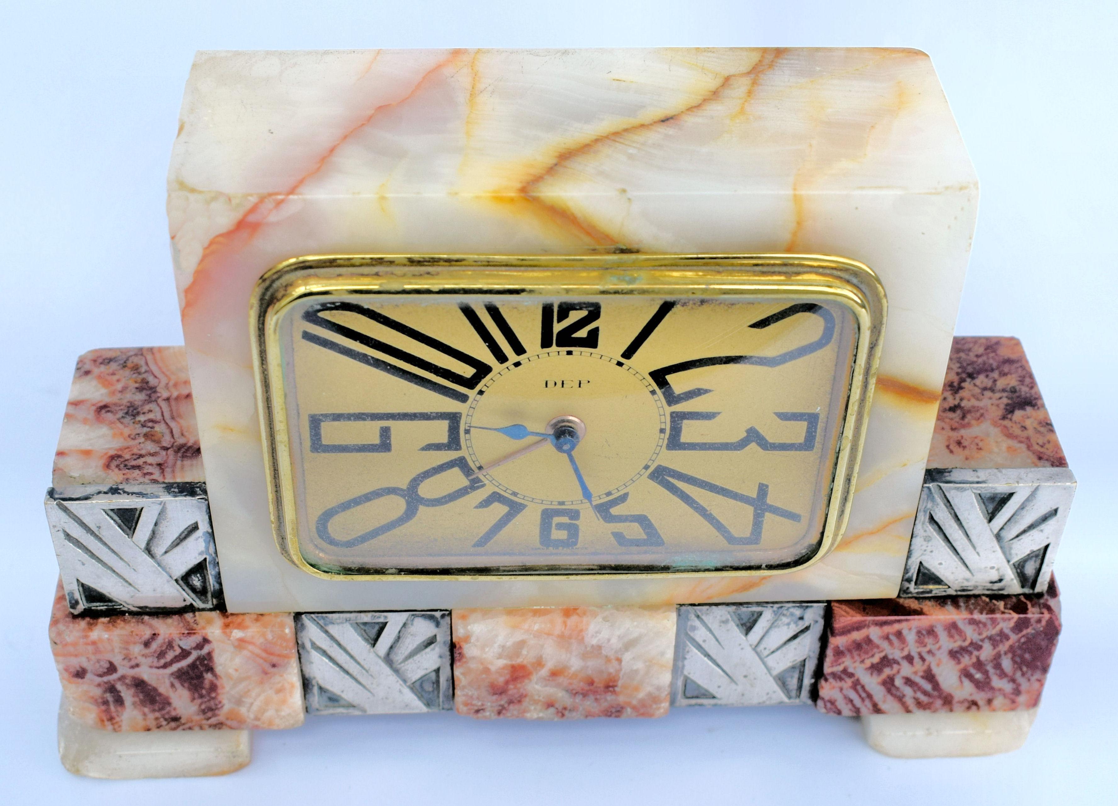 Very striking and distinctive looking 1930s Art Deco French clock by French clockmakers Dep. The case is solid multi colored marble, the bezel and face are in gold tone metal. There are silvered spelter accents adding more decoration to the exterior