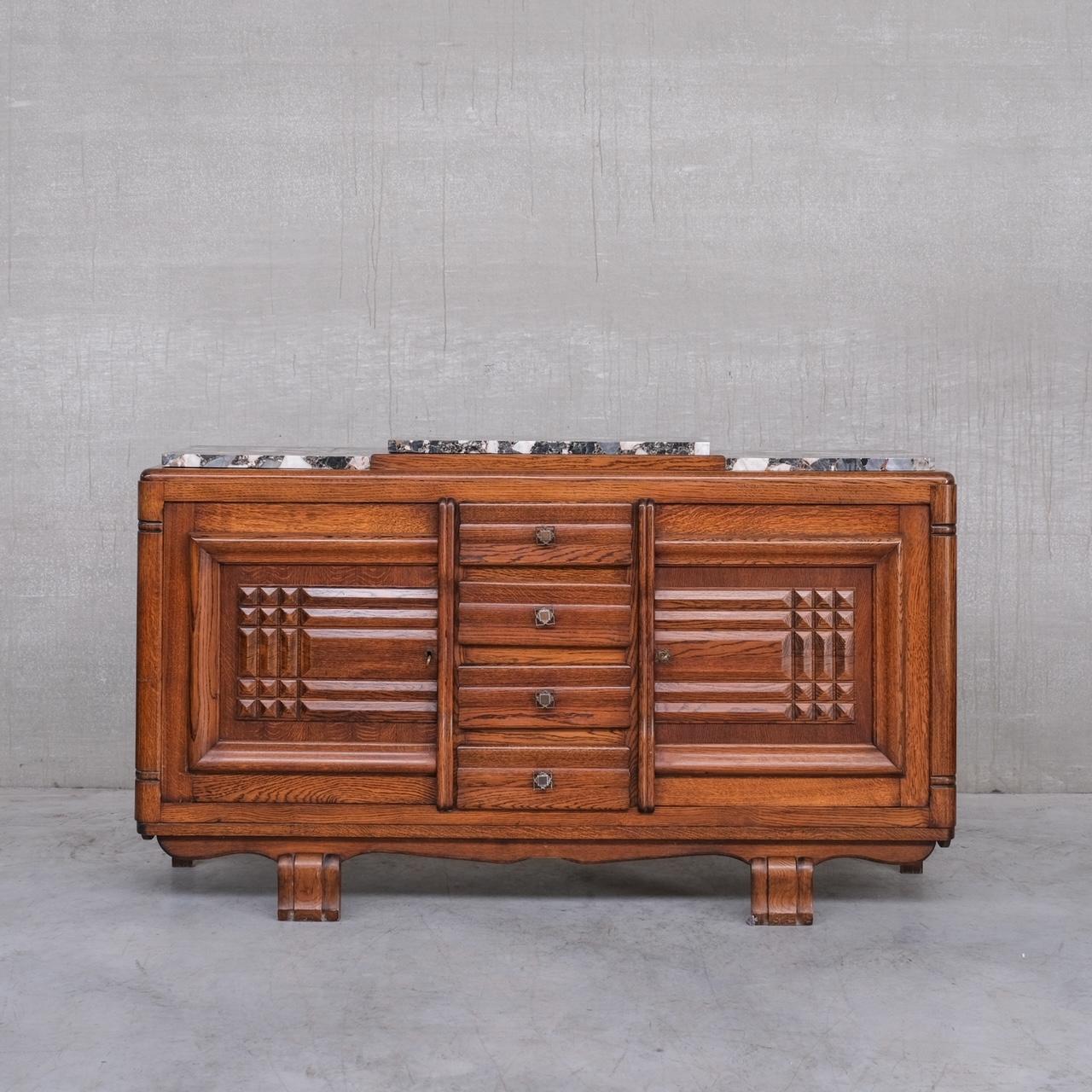 A French late Art Deco sideboard, likely by Gaston Poisson. 

France, c1940s. 

Oak and marble. 

The marble top has some chips and nicks, it could easily be replaced. 

Original keys retained. 

Location: Belgium Gallery. 

Dimensions:
