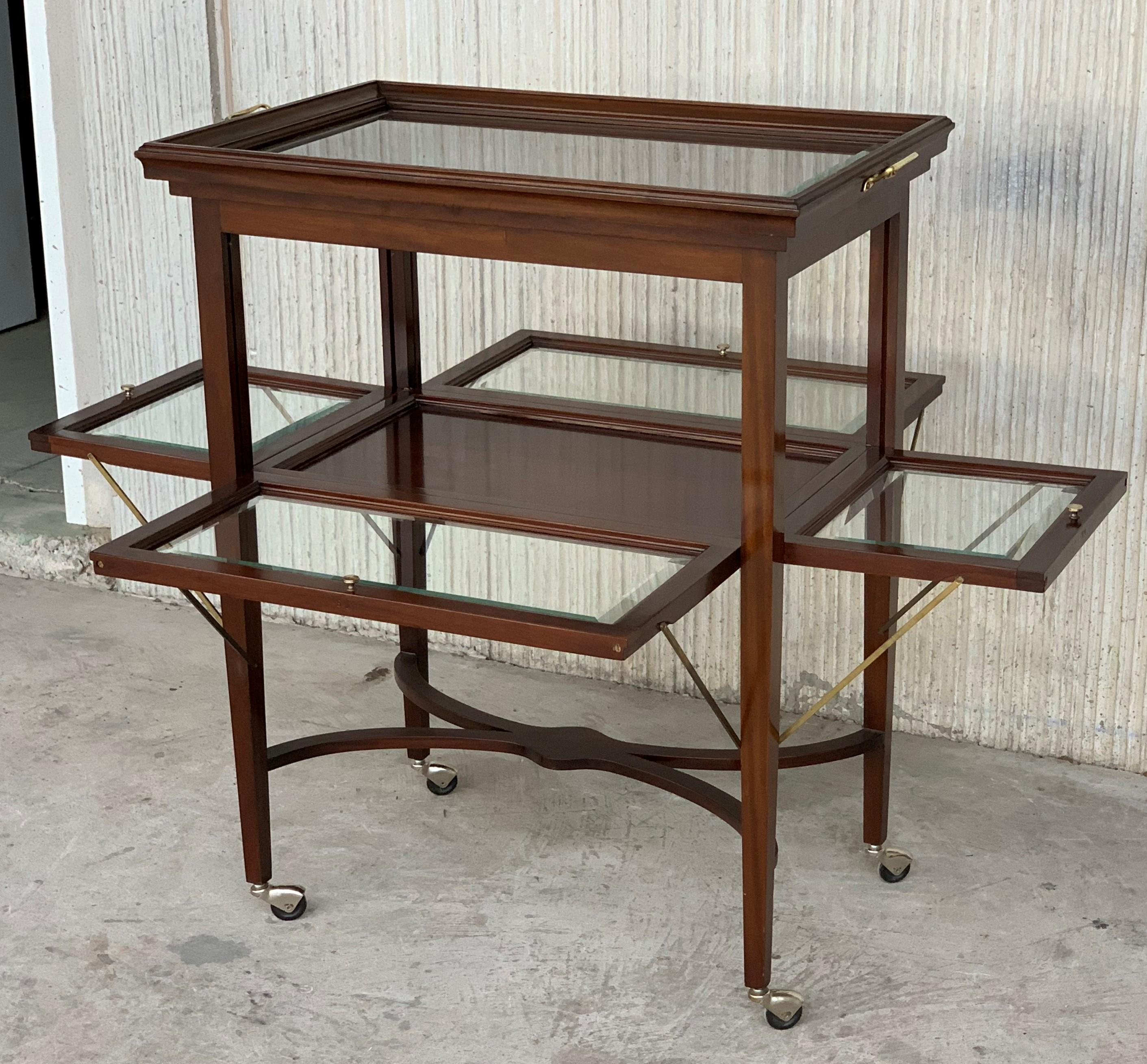 A vintage neoclassical convertible mahogany tea table, French, circa 1920. Square tapered legs in mahogany, glass tray tabletop and shelves, all with delicate bands of brass inlay for subtle decoration. The removable tray has scalloped edges and a