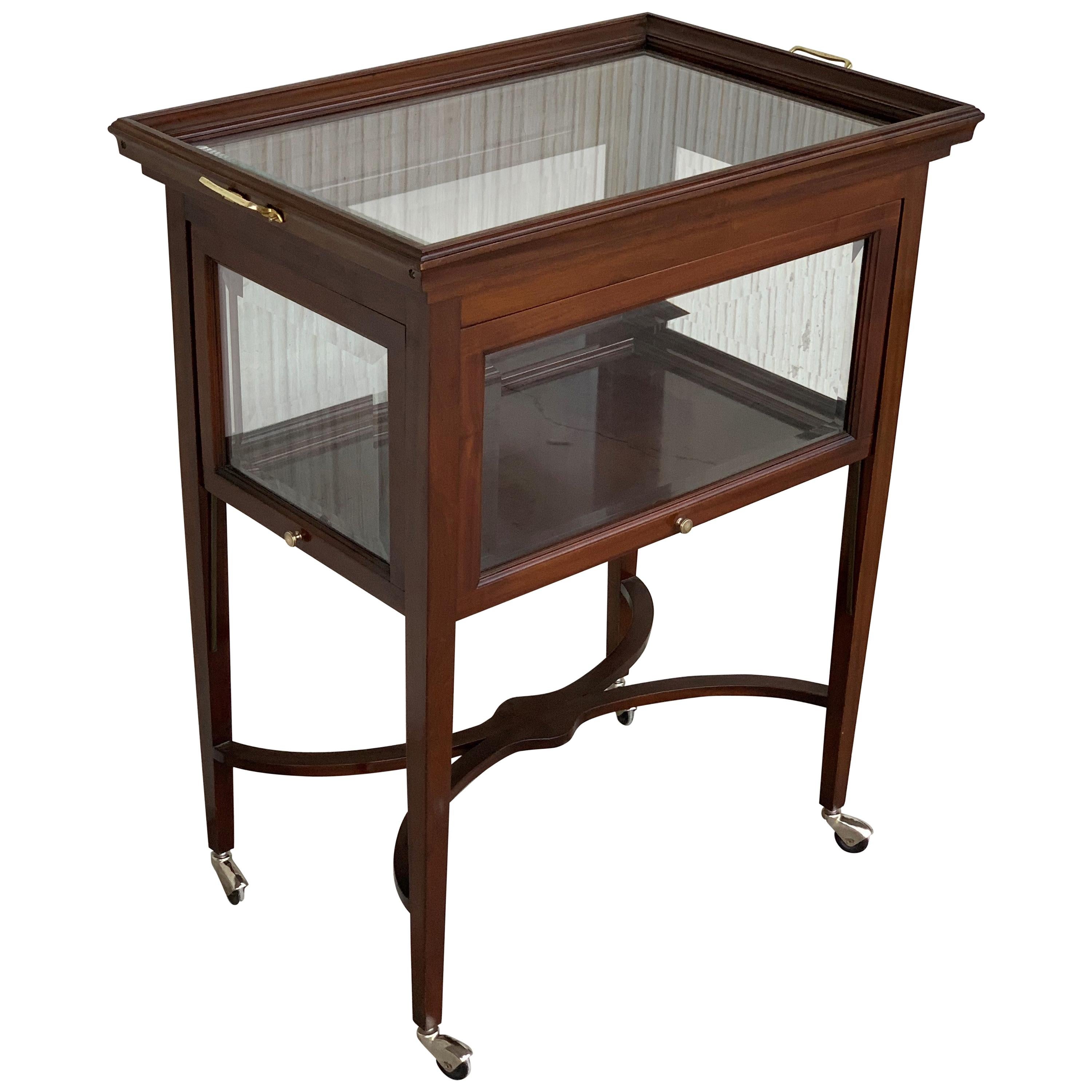 A vintage neoclassical convertible mahogany tea table, French, circa 1920. Square tapered legs in mahogany, glass tray tabletop and shelves, all with delicate bands of brass inlay for subtle decoration. The removable tray has scalloped edges and a