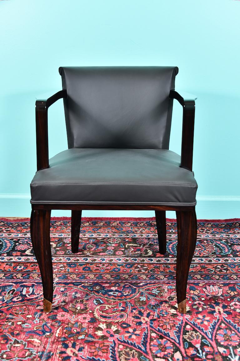 Französischer Art-Deco-Stuhl aus Makassar-Holz, neu gepolstert mit dunkelbraunem Leder. Die Rückenlehne des Stuhls ist oben leicht gebogen. Die Vorderbeine sind leicht gebogen und haben dekorative Messingspitzen. 
Der Zustand ist