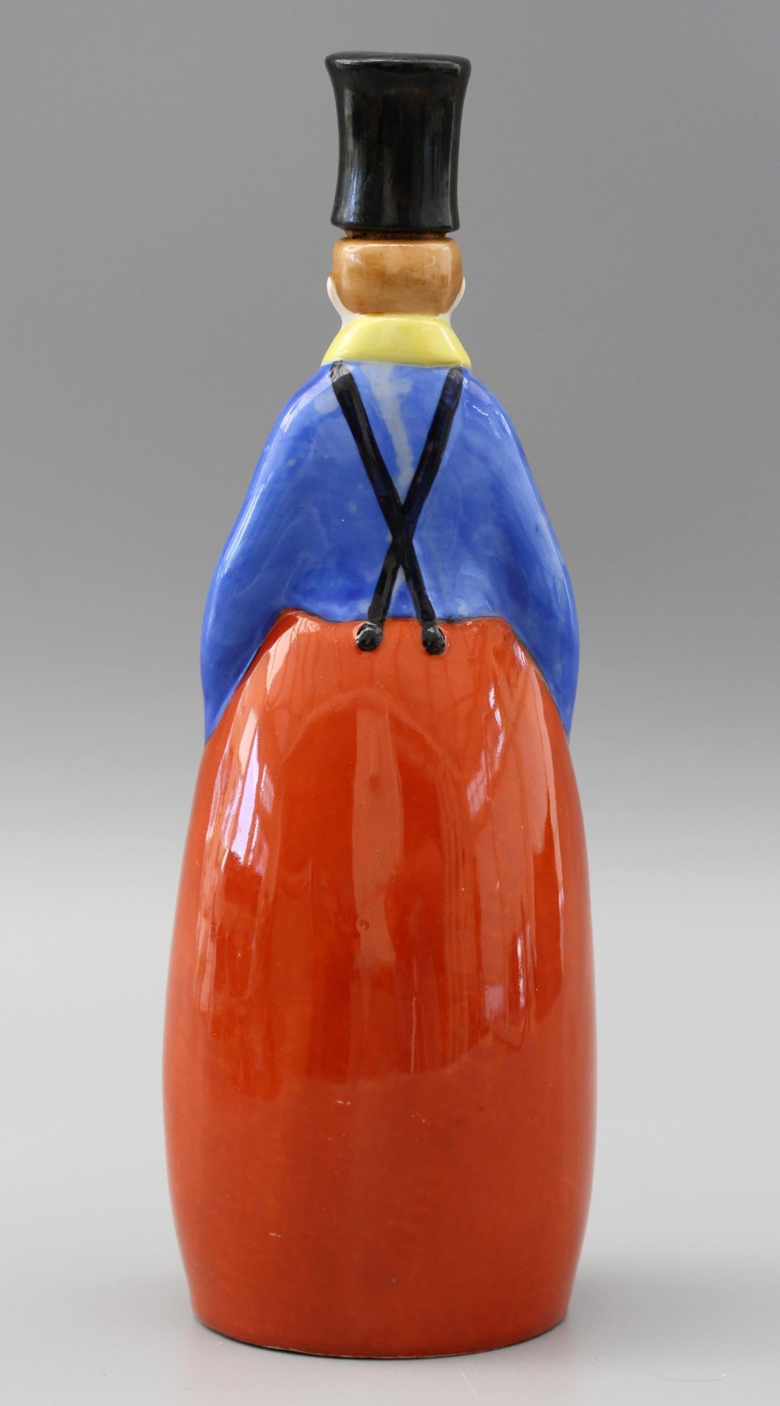 A delightful French Art Deco porcelain bottle, attributed to ROBJ Paris, modeled as a young boy wearing a tall hat dating from circa 1930. The finely made bottle portrays the boy standing his hands in his pockets and the apron held up by braces with