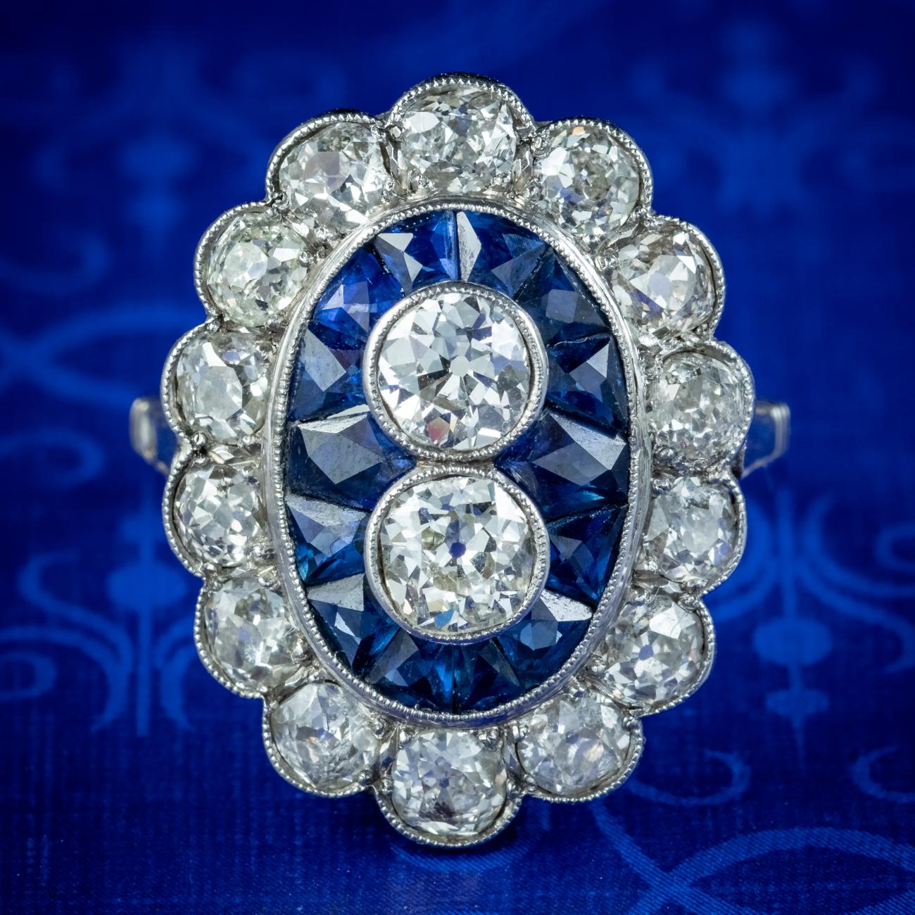 A magnificent Art Deco cluster ring made in France in the 1920s. It features twin old European cut diamonds set in the centre, framed in a border of calibre set, French cut sapphires and fourteen old cut diamonds.

The sapphires total to approx.