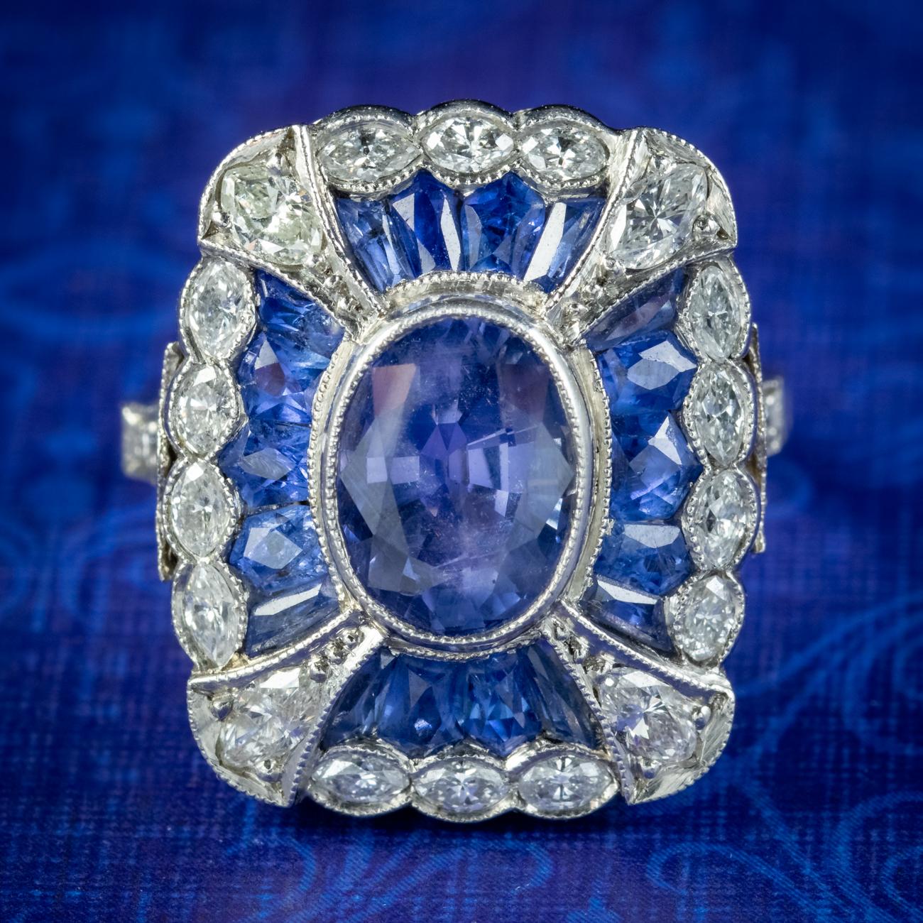 An extravagant Art Deco cocktail ring made in France, Circa 1920. The large face is decorated with an array of marquise cut diamonds, French cut sapphires and a larger oval cut sapphire bezel set in the centre (approx. 1.70ct). 

The blue sapphires