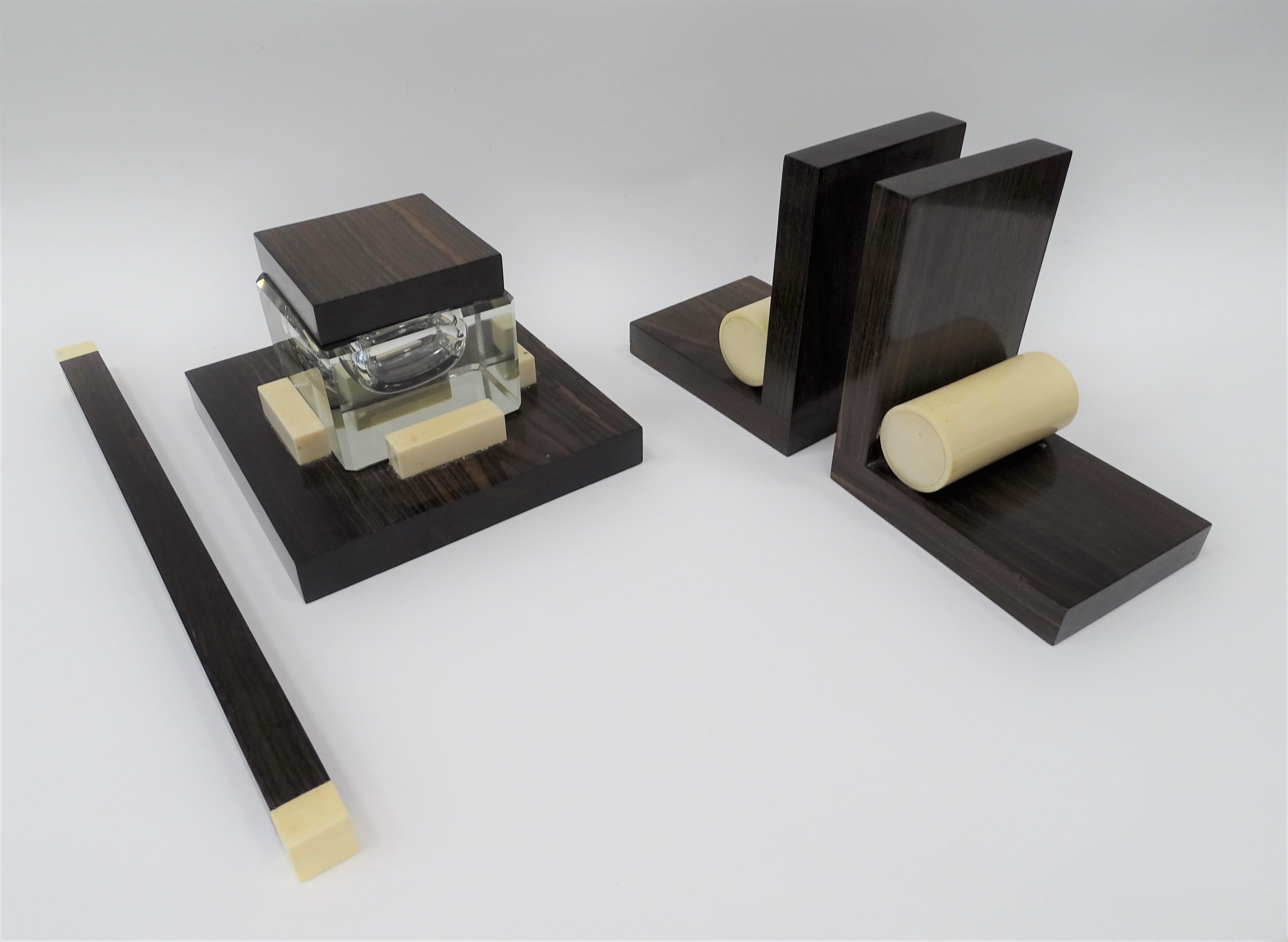 Gorgeous and very refined Art Deco French writing set made of hardwood, inlaid bone simil and glass. The complete set is preserved in perfect condition, consisting of the inkwell, the blotter, the ruler and the bookend. Elegance, functionality and
