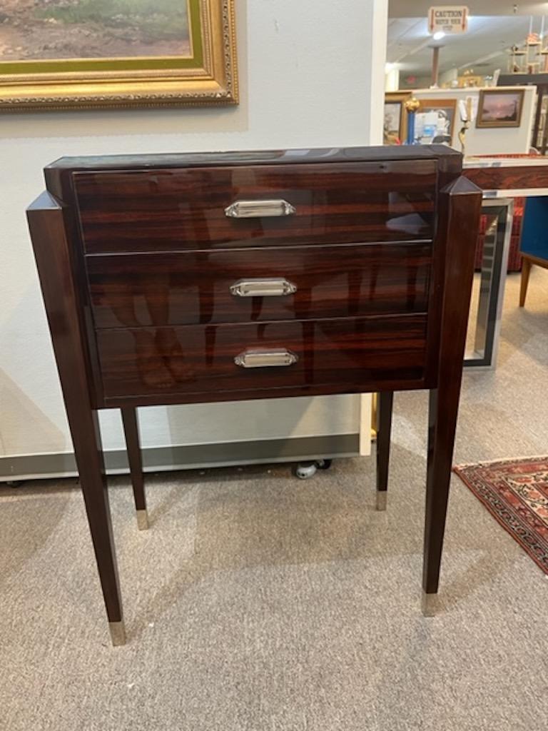 Side table is made out of palisander wood. Has 3 spacious drawers with rectangular chrome handles. Elevated by 4 slim legs that have chrome decorative elements on the bottom.

Condition is perfect, restored
France, c. 1930s
Size: 22”W x 15”D x