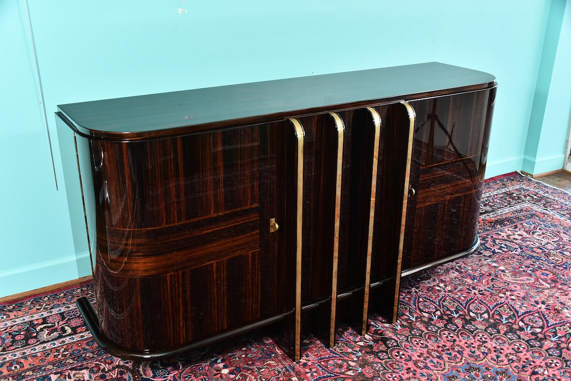 Art Deco French sideboard with 4 brass vertical lines

Sideboard is made out of Macassar wood. It has 2 keyed spacious drawers on the sides. Inside there are shelves and smaller drawers. Between side drawers there are 4 decorative brass vertical