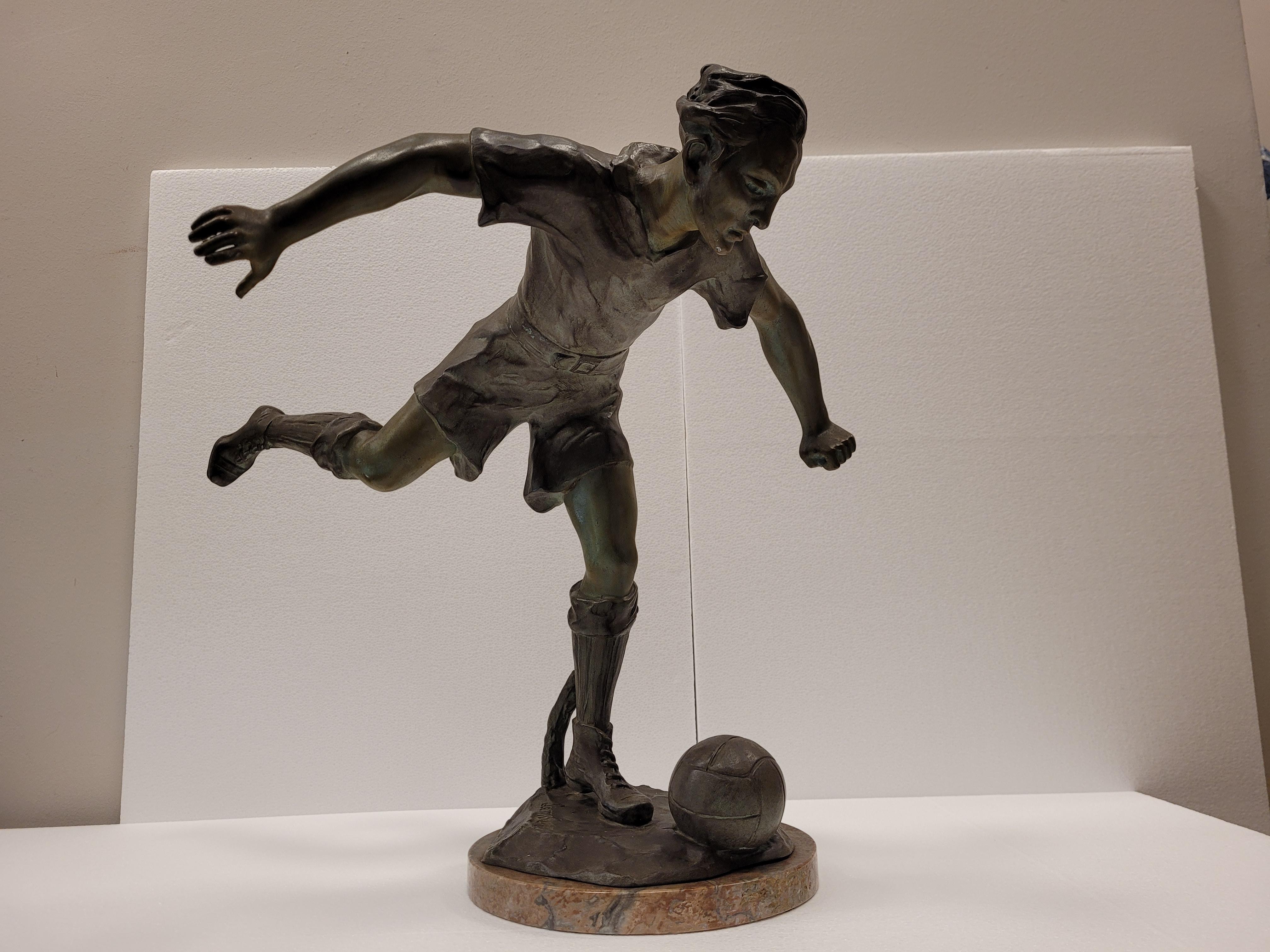 Amazing sculpture that represents a soccer player, just in the moment before kicking the ball under his feet. The athlete draws back his arms and one of his legs, balancing on the other. Both clothing and hair are also represented according to rapid