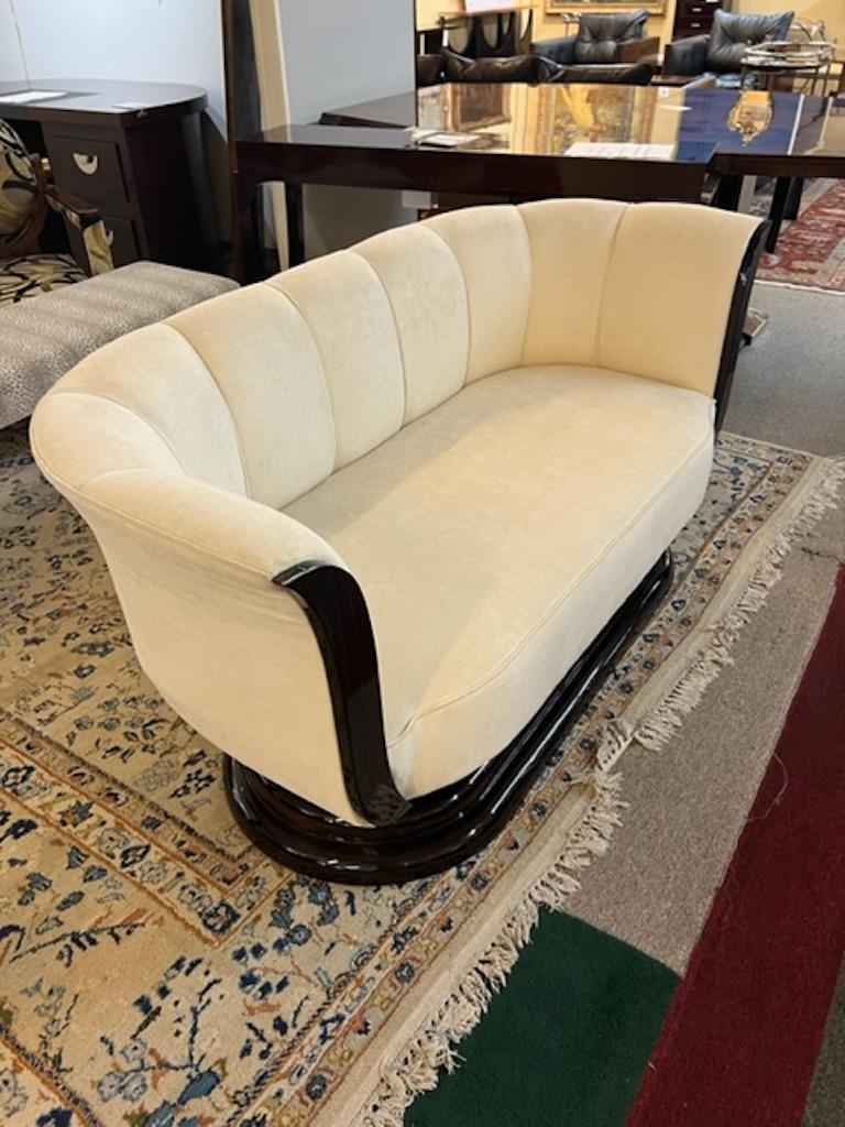 Elegant Art Deco sofa made out of Macassar wood. Has curved back and decorative wood elements on the sides to create contrast between light fabric and dark wood. Elevated by wide stable base built out of 3 oval pieces of wood, that are placed one on