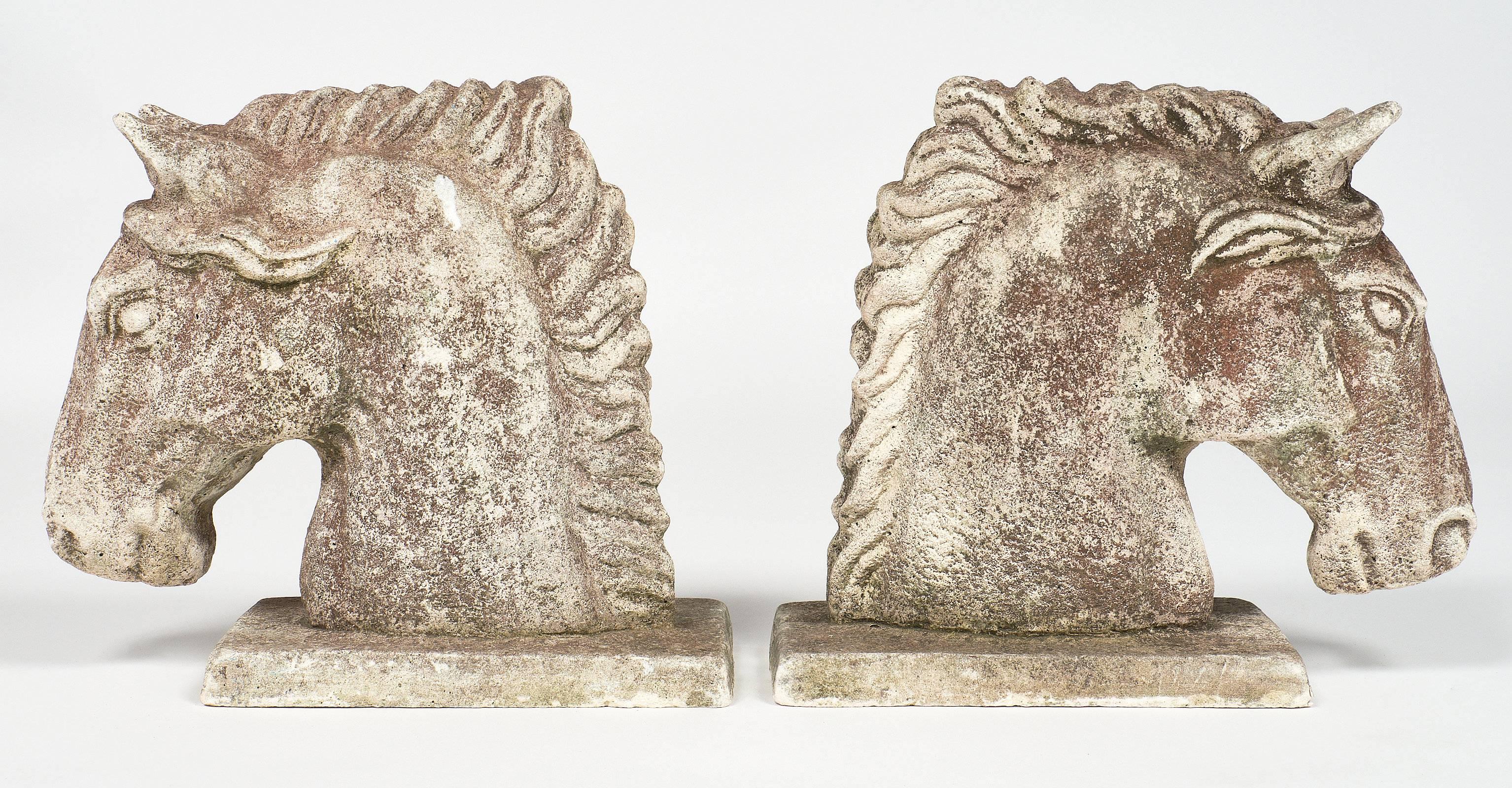 A pair of Etruscan reconstituted stone horse heads with an Art Deco feel and a light patina.