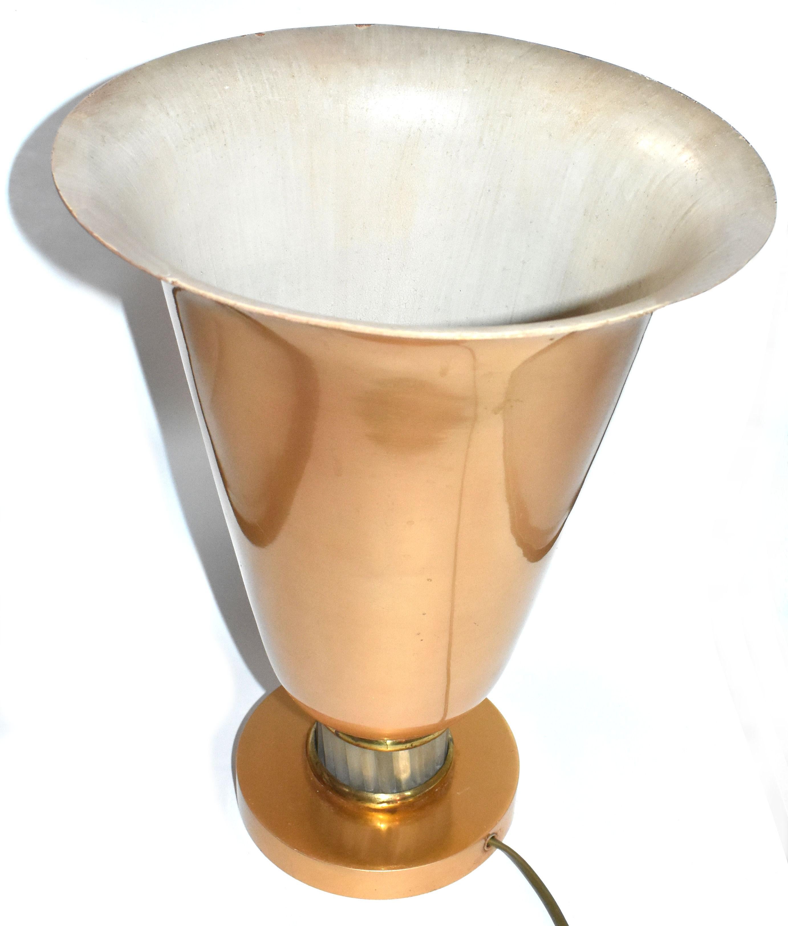 A lovely example of an Art Deco table uplighter that shows great style and imagination. It is made from a Spun aluminium and then decorated with a pale gold tone finish. It is cream on the inside and takes a normal bulb. There are sections of glass
