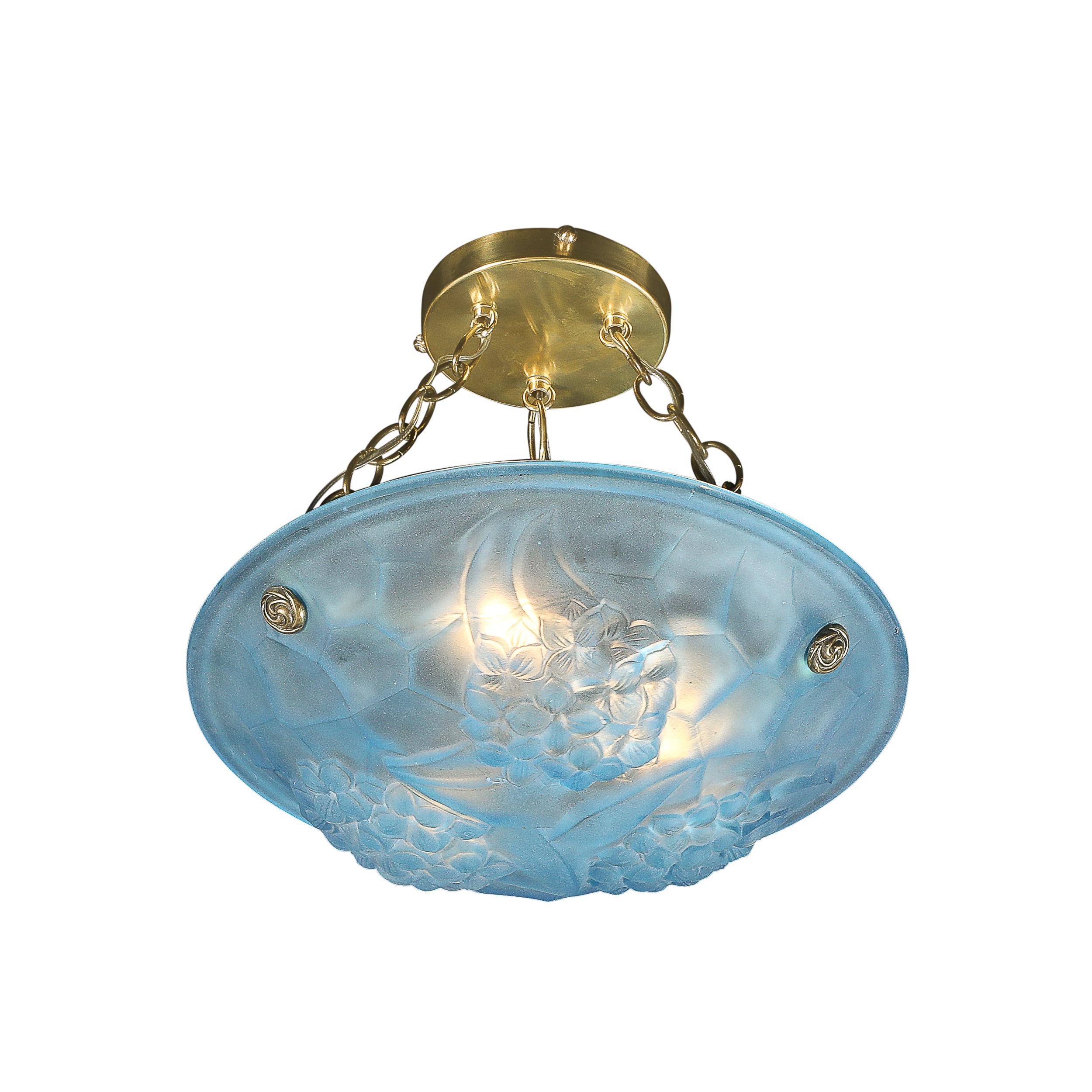 Ce lustre pendentif en verre bleu givré de style Art déco, aux couleurs saisissantes et aux accessoires en laiton, signé ROC par Degué, est originaire de France, vers 1930. L'abat-jour rond en verre bleu moulé et dépoli est orné de grappes de fleurs