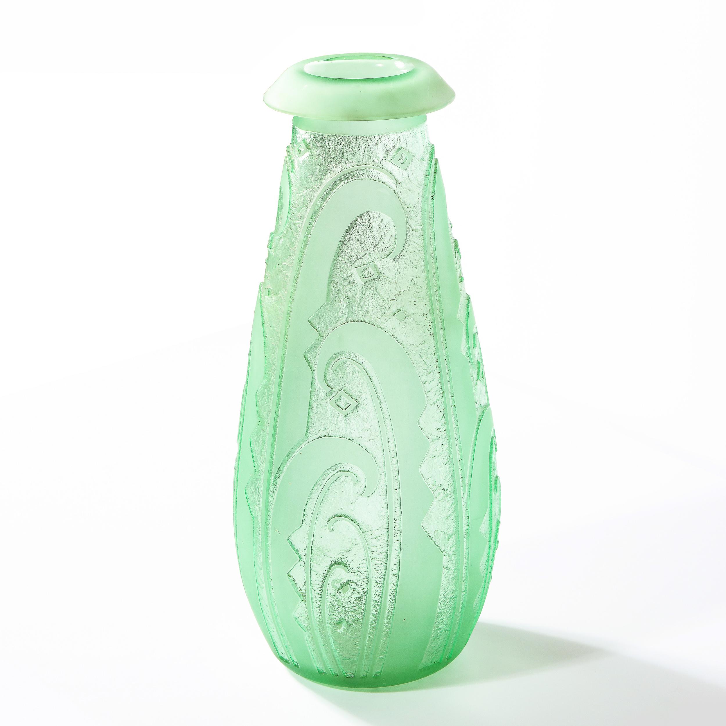 This refined Art Deco vase was realized and signed Nancy Daum in France circa 1930. It features a tapered conical body with a cantilevered mouth in frosted celadon glass with streamlined curvilinear cubist detailing etched throughout the textured