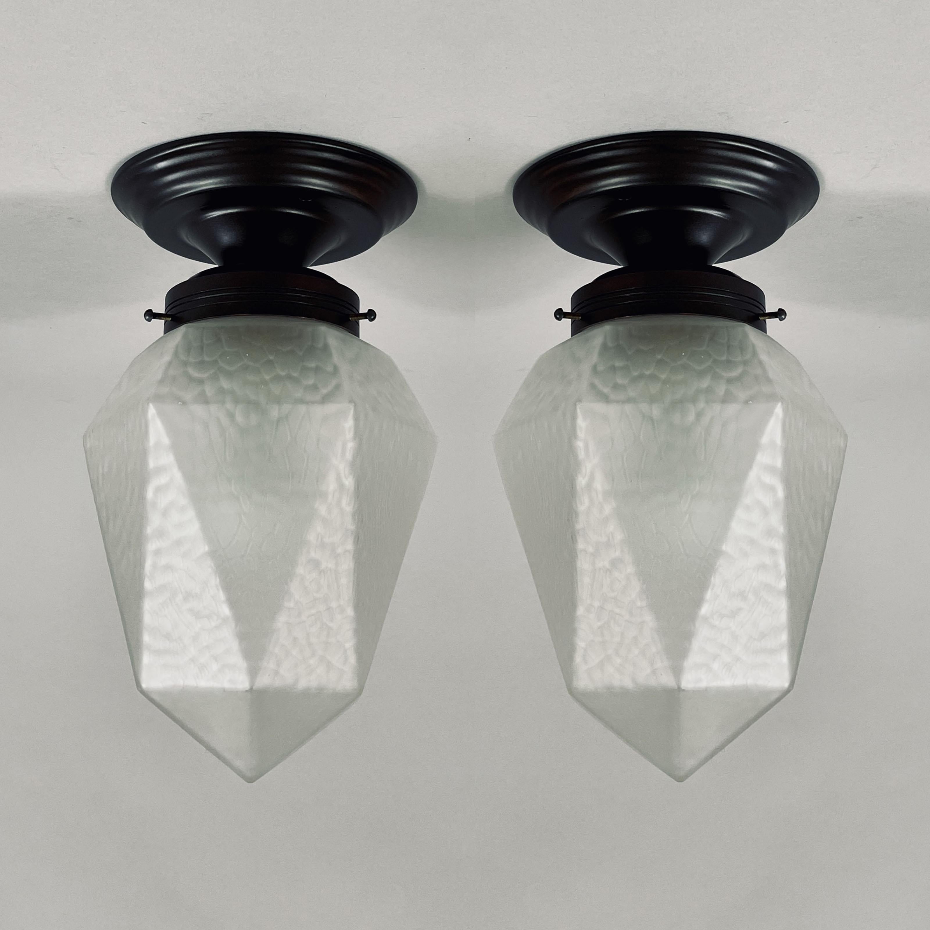 These elegant flush mounts were designed and manufactured in Sweden in the 1920s. 

The lights feature faceted, geometric frosted glass shades with a  hammered texture that softens and diffuses the light beautifully. Each shade forms a tapered