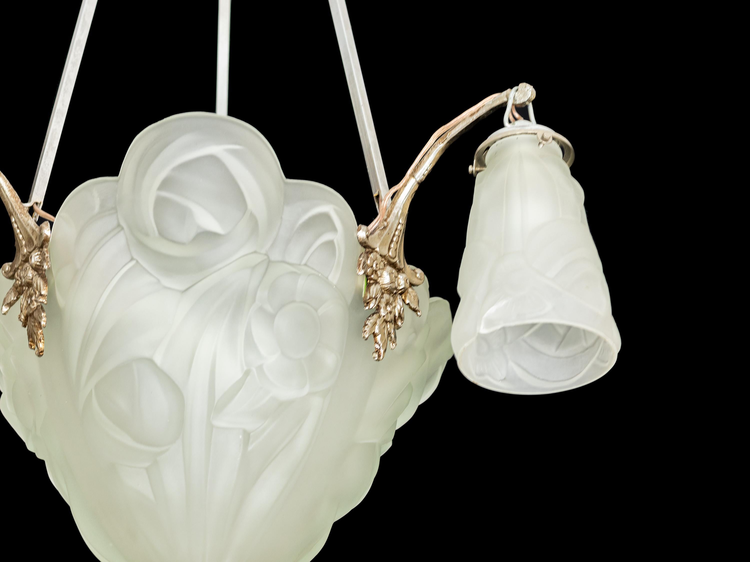 Un lampadario Art Déco disegnato da Henri Petitot e prodotto da David Gueron per Verrerie D'Art Degué. 
Questo lampadario è caratterizzato da una ciotola in vetro geometrico smerigliato e da paralumi a forma di tulipano, sospesi da bracci nichelati