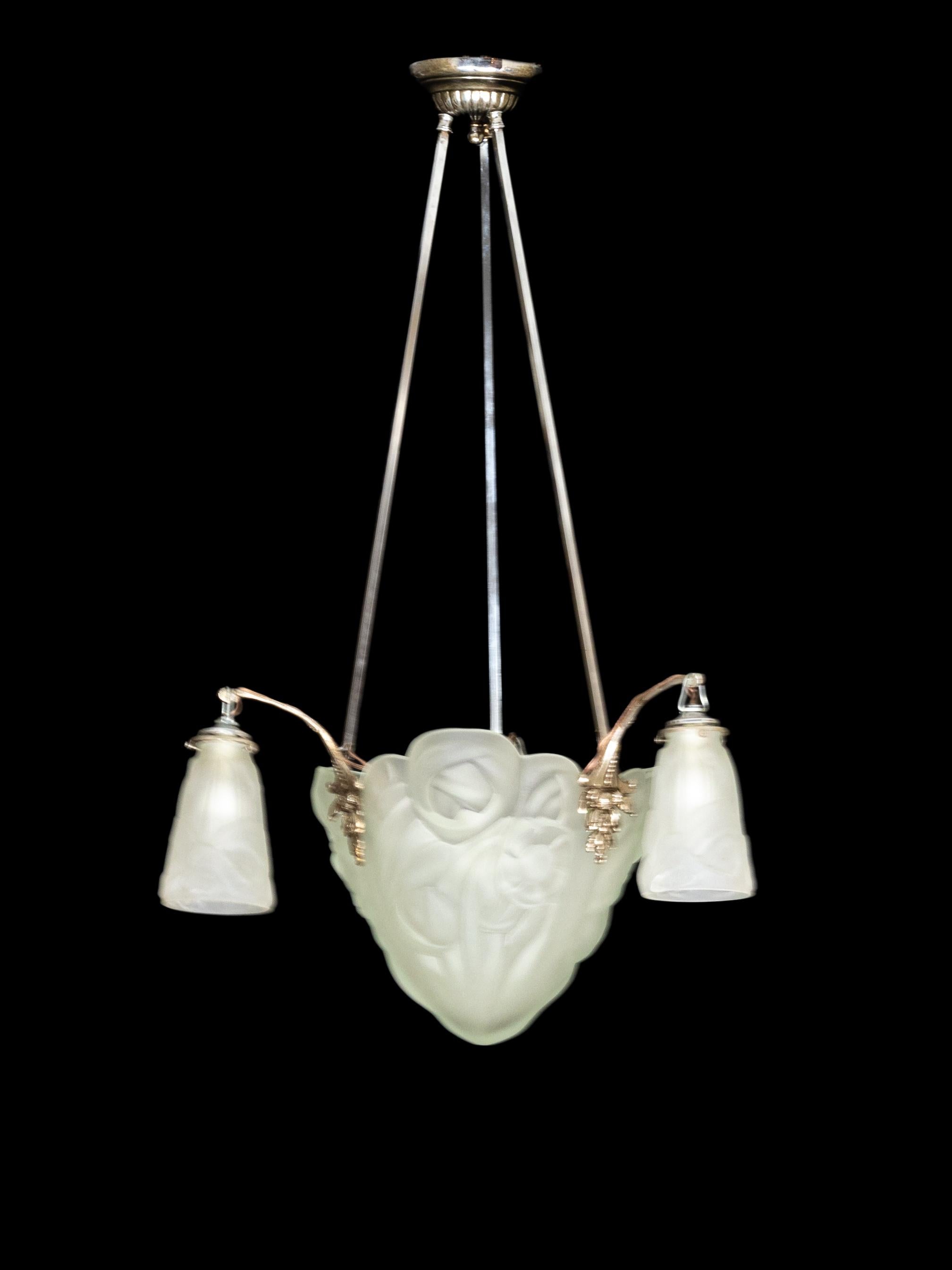 Araña Art Déco con cuenco de cristal geométrico esmerilado y pantallas en forma de tulipán, suspendida de brazos niquelados decorados con monturas vegetales, diseñada por Henri Petitot y producida por David Gueron para Verrerie D'Art Degué. 

El