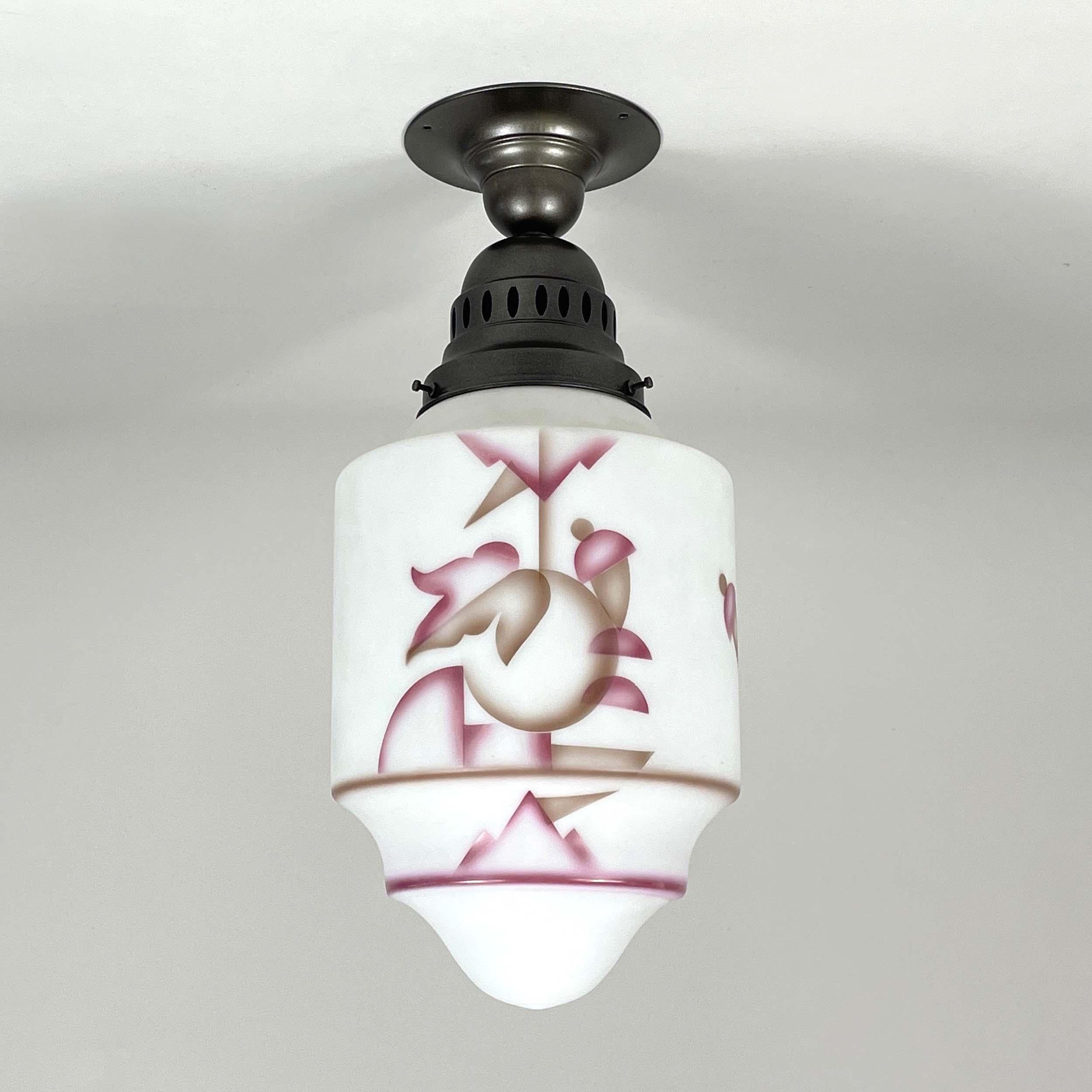 This elegant flush mount was designed and manufactured in Germany in the 1930s during the Bauhaus period. It features a white frosted glass lampshade with rose and light brown colored paintbrush decor and bronzed/burnished hardware.

The light has