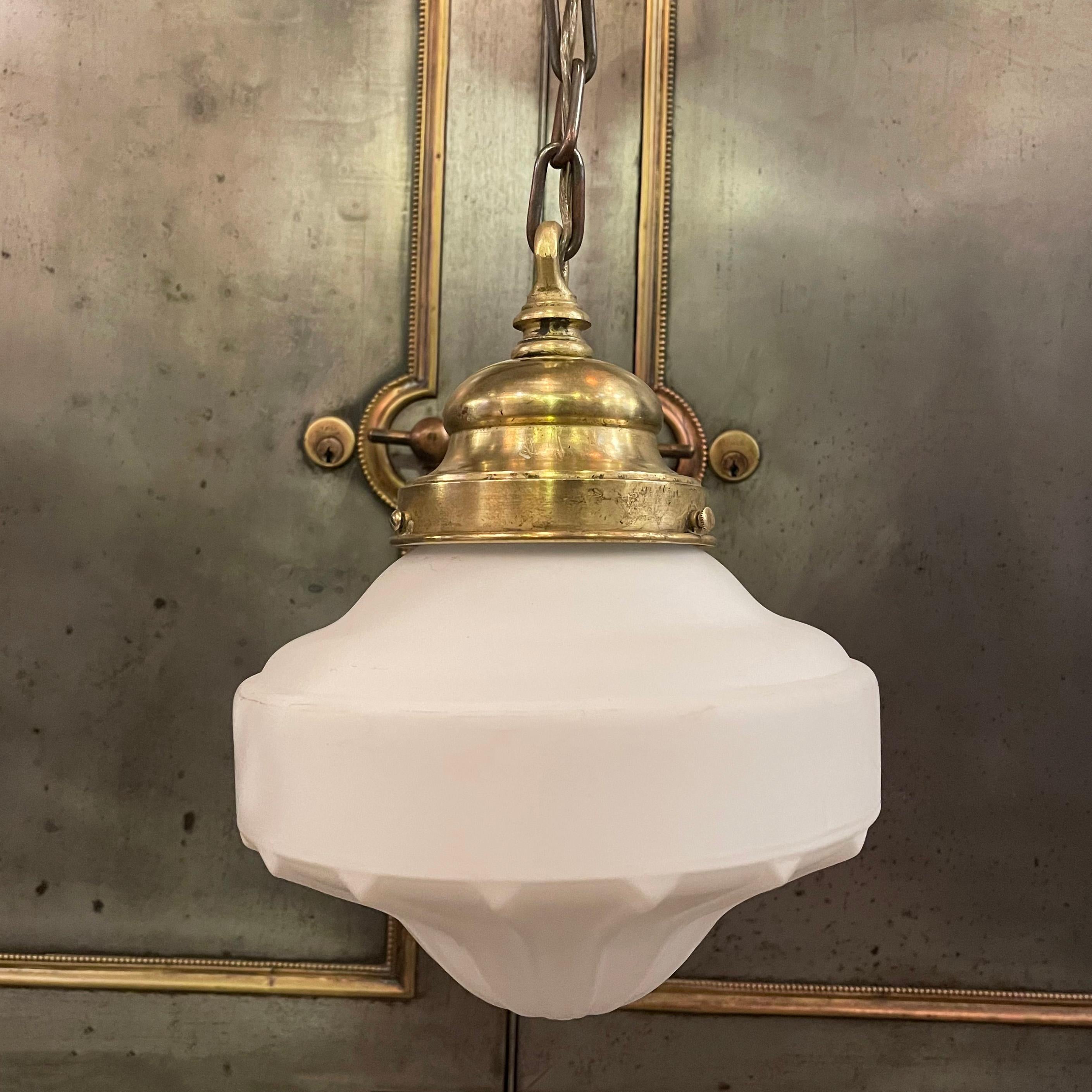 Art Deco pendant light features a saucer shape, frosted glass shade with ridged bottom with brass hardware including fitter, chain link and ceiling canopy. The pendant hangs at an overall height of 22 inches an can be shortened. The fixture height