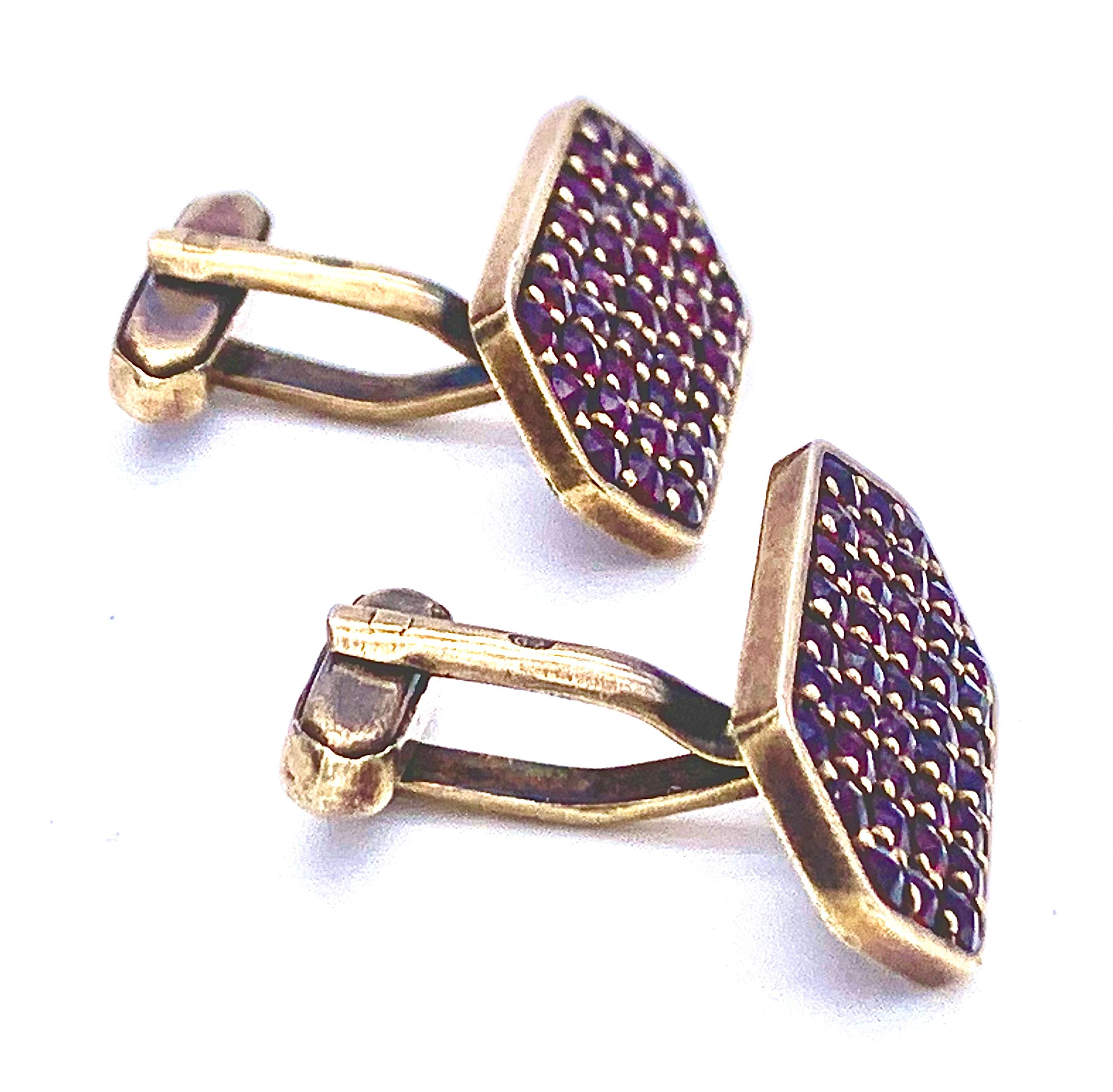 The hexagonal cufflinks are made out of silver and guilt in a red gold hue. They have been set with round cut bohemian garnets. 