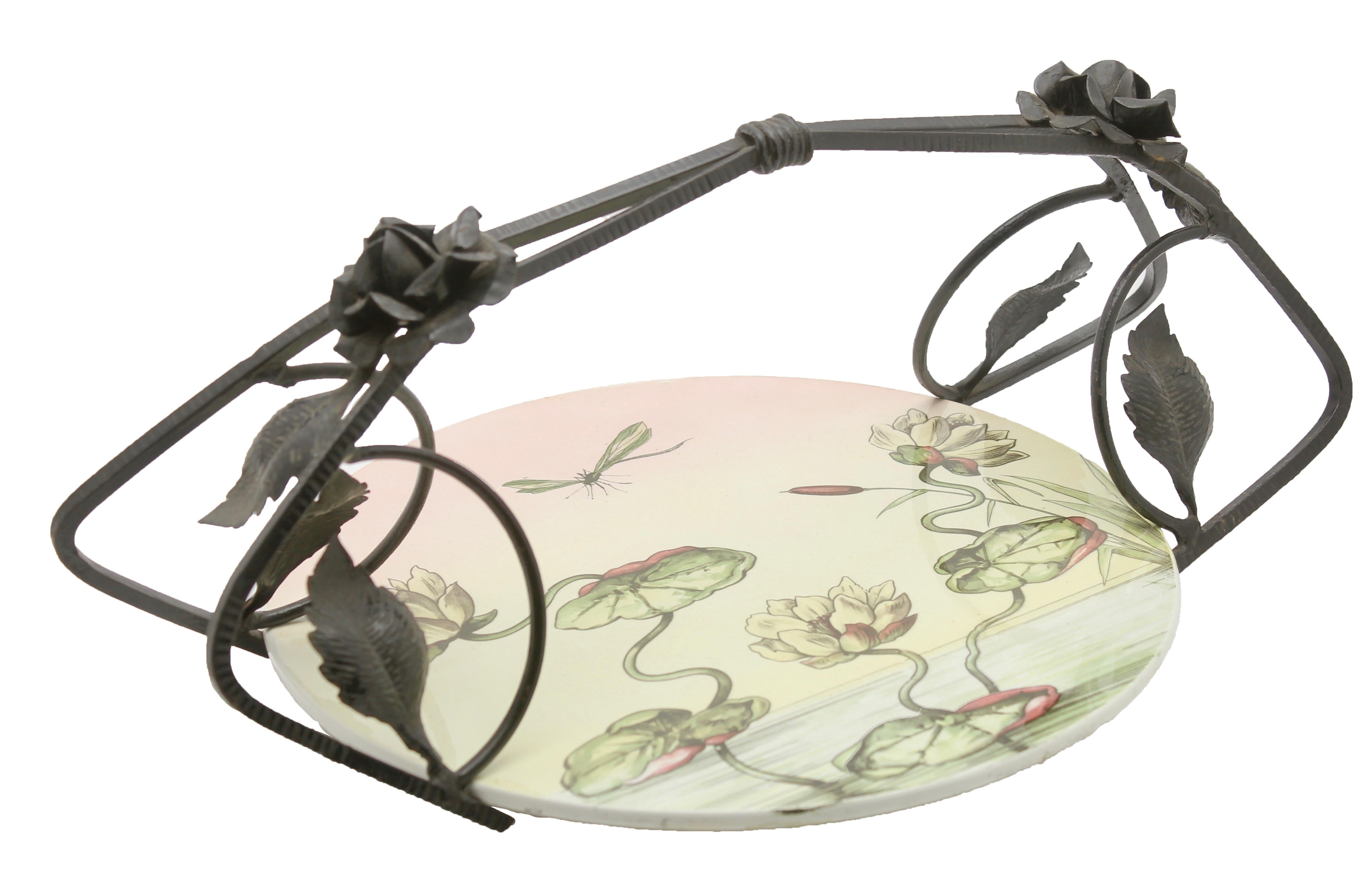 This unusual Belgian piece has the hallmarks of Art Nouveau and combines a ceramic gateau plate in a wrought iron carrier, 
The ceramic plate produced in Germany, features an Art Nouveau design of waterlillies and was produced, 1910-1920.

The