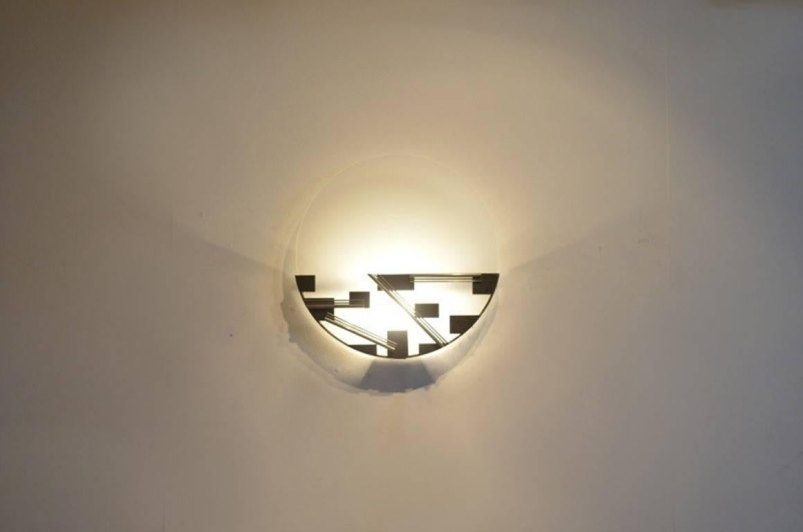 Modernist wall sconce with geometrical shaped metal detailing on the bottom half of the shade with black painted overall base (squares).