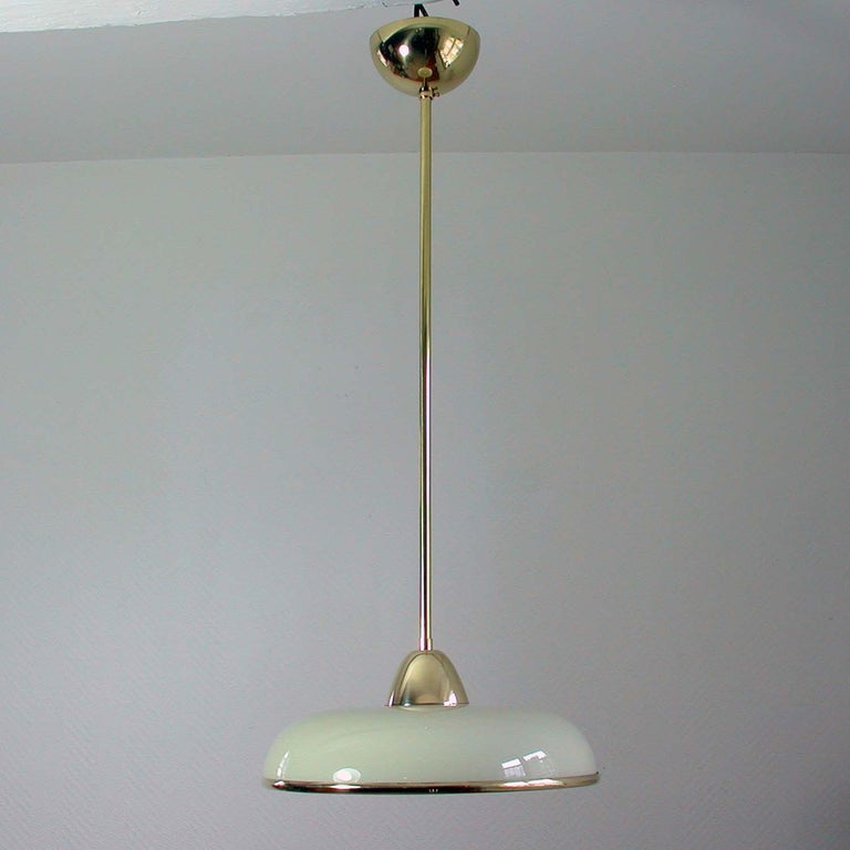 This elegant pair German pendants was designed and made in Germany in the 1930s. The lamps are made of brass and have got a cream colored Opaline glass shade in typical Bauhaus design with a brass rim. Good vintage condition with one E27 socket per