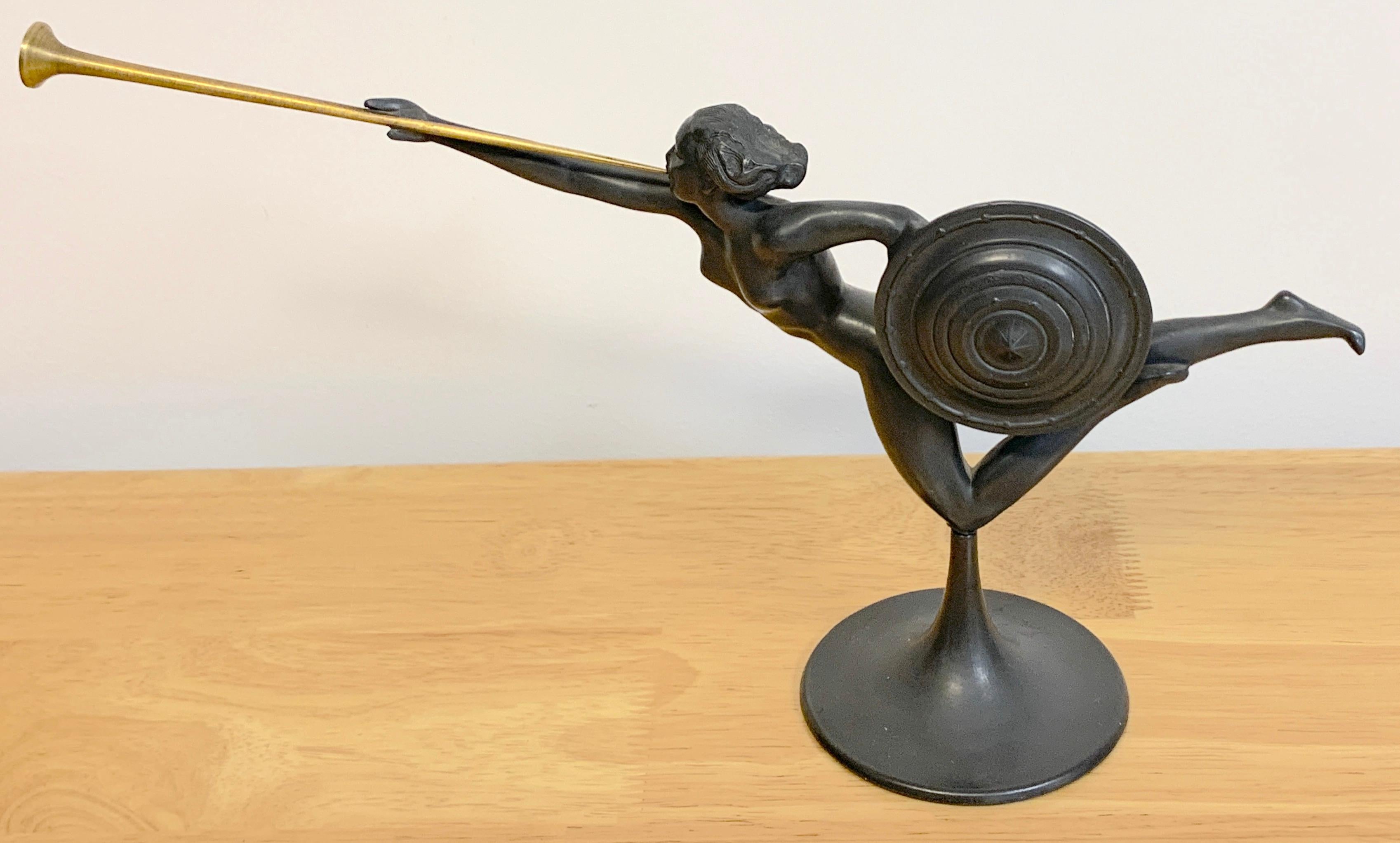 Sculpture d'allegorie Art Déco en étain et laiton attribuée à Kayserzinn
Allemagne, Vers 1925

En deux parties, la femme guerrière nue flottante tenant un bouclier et  trompette en laiton, reposant sur un piédestal rond. Non marqué 