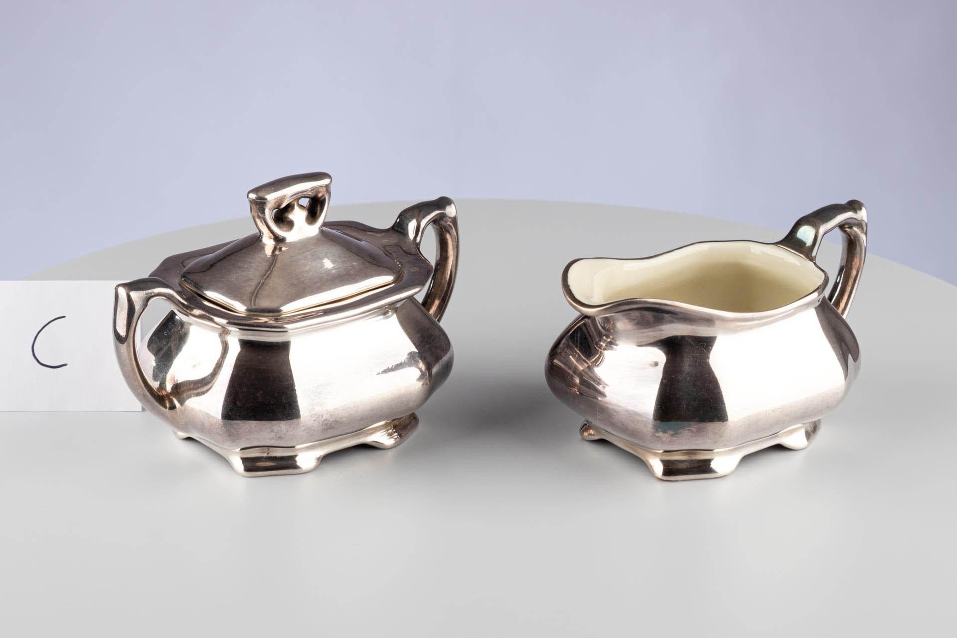 Art Deco German Silver Lustre Porcelain Sugar Bowl Jug WMF Königszelt Porzellan

German
Porcelain 
c. 1920s/ 1930s 

Dimensions: H x W x D: 
Sugar bowl : 9cm x 12.5cm x 8cm 
Jug : 7cm x 12cm x 8cm 

This rare Art Deco silver-lustre porcelain set