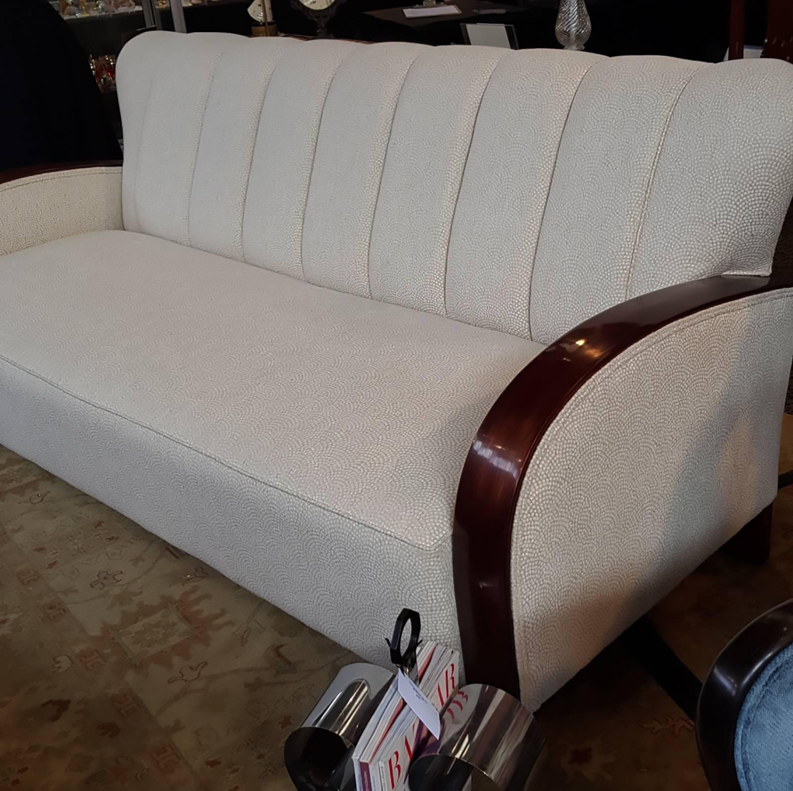 A spectacular Art Deco sofa with bent curved arms. In excellent condition being recently restored and reupholstered in a commercial quality ivory coloured fabric that has the Champagne pattern of expanding circles of “bubbles”, symmetrically aligned