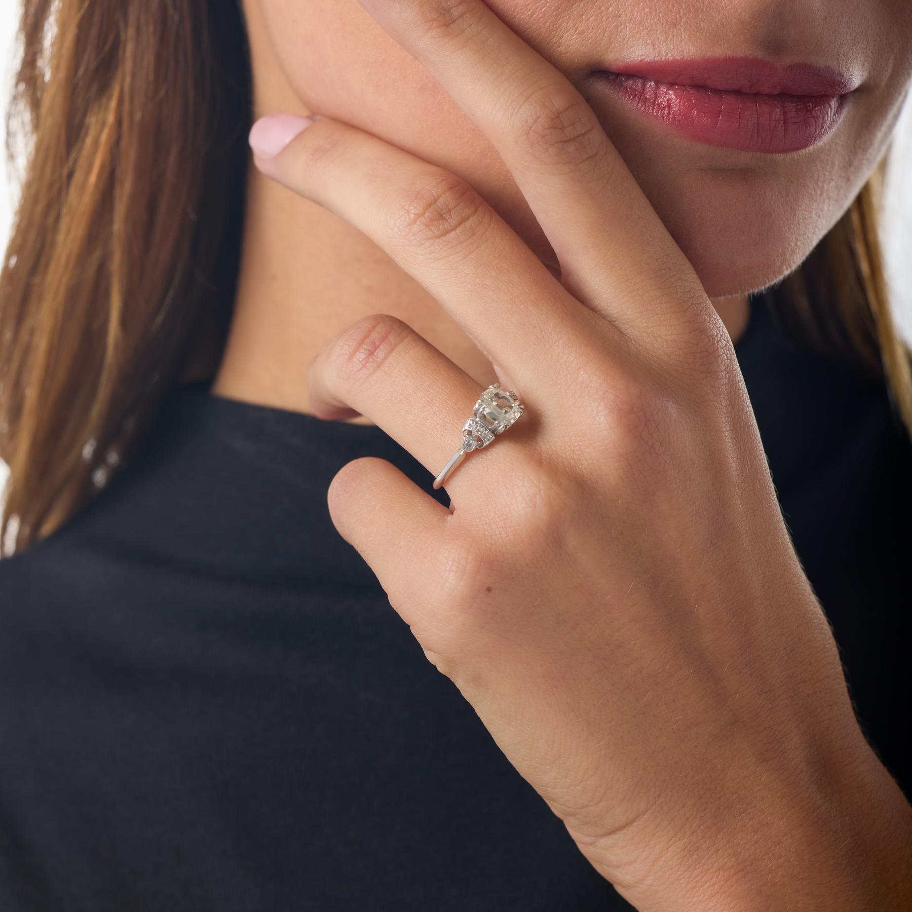 Cette bague de fiançailles Art déco célèbre la géométrie audacieuse et l'éclat raffiné de l'époque, avec au centre un diamant taille ancienne magnifiquement proportionné dont le feu doux brille chaleureusement dans sa monture en platine. Les