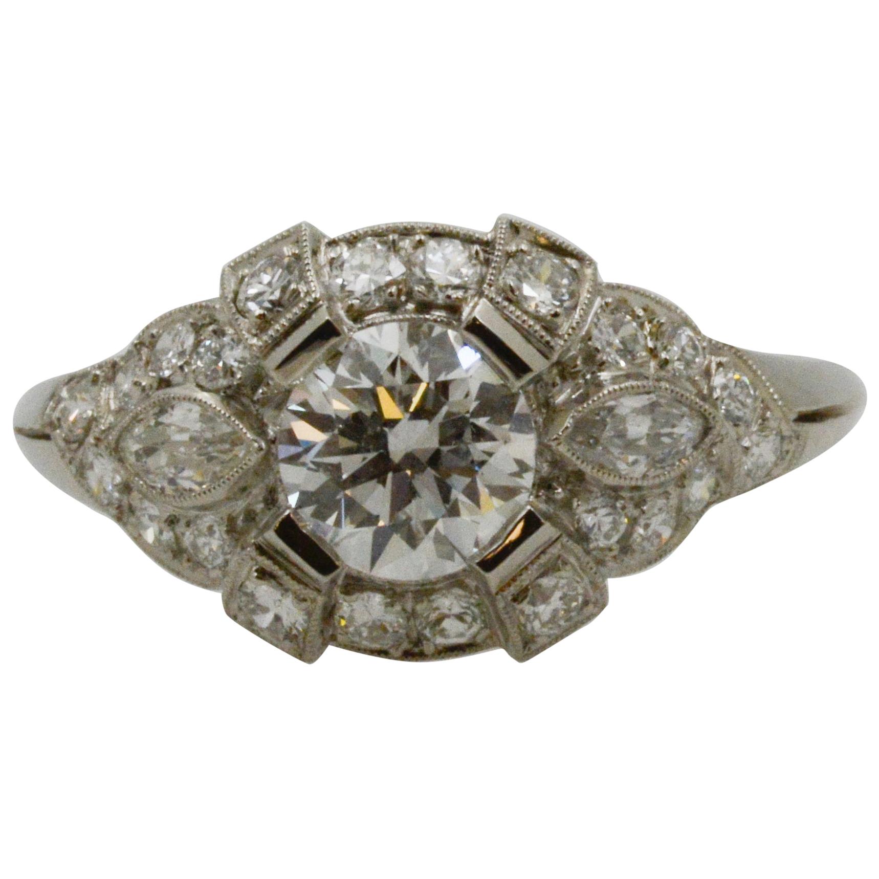 This platinum Art Deco Style GIA certified ring features round brilliant cut diamonds weighing an approximate 0.90 combined carats with E coloring, and SI2 clarity, and 22 European cut diamonds weighing an approximate 0.25 combined carats, and two