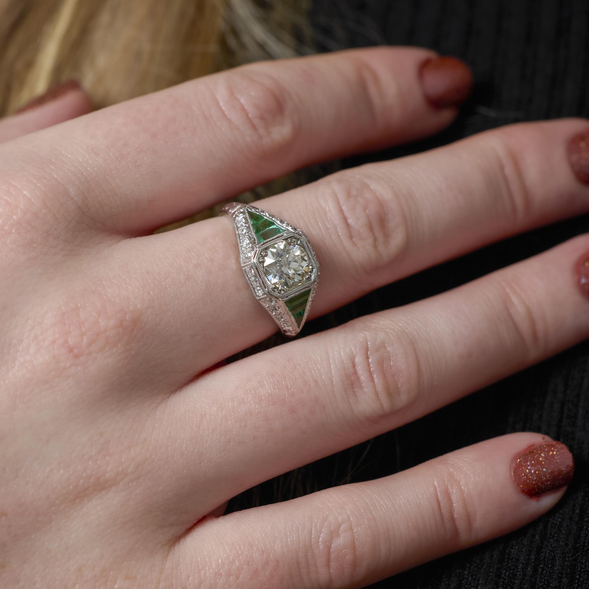 Cette bague Art déco en platine des années 1930 est ornée d'un diamant de taille européenne ancienne de 1,31 carat certifié par la GIA, rehaussé de diamants étincelants et d'émeraudes de taille calibre vif. Son design géométrique audacieux et le