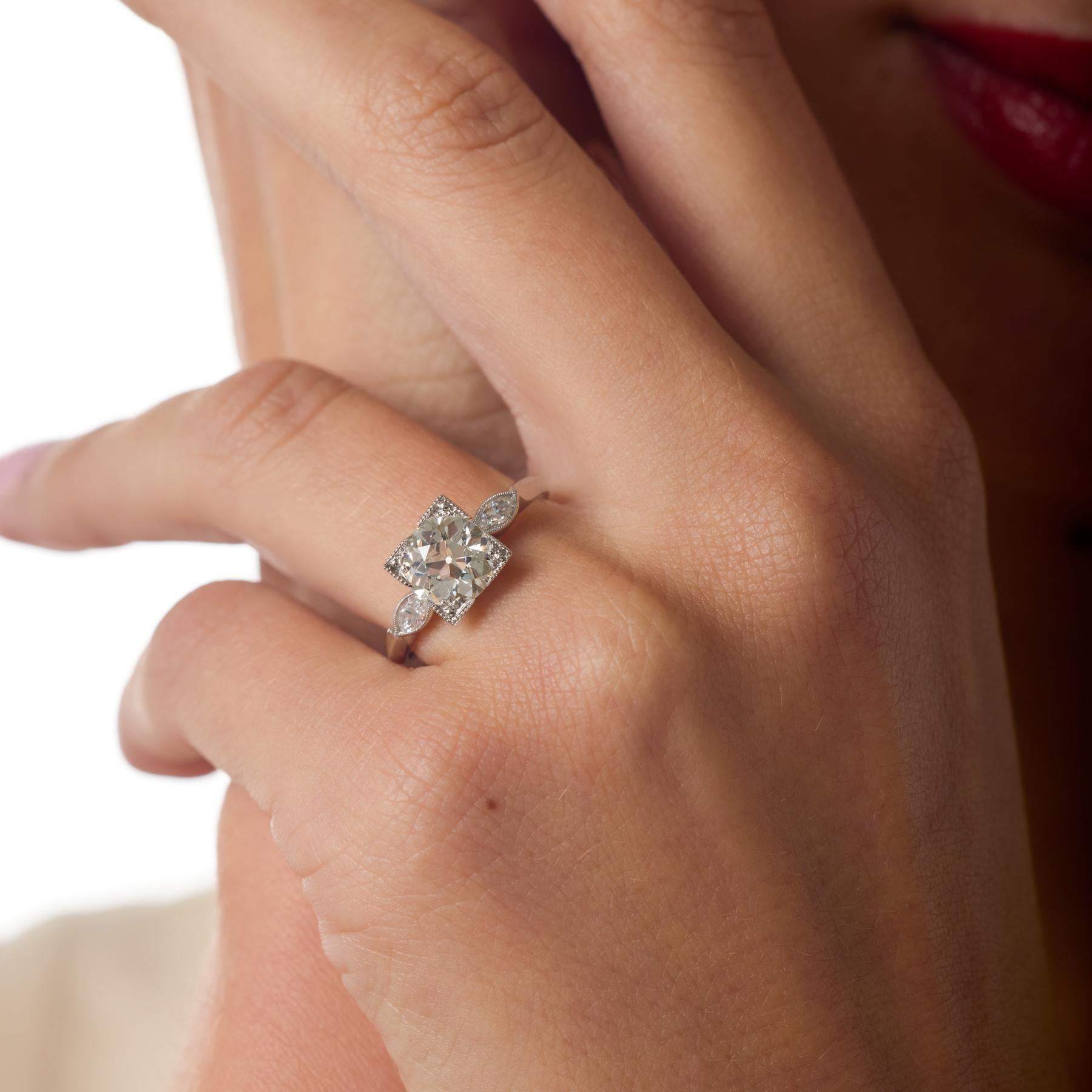 Questo squisito anello di fidanzamento Art Déco è incentrato su un luminoso diamante Brilliante Antico Europeo da 1,65 carati, il cui taglio storico irradia un bagliore caldo e romantico. Due diamanti marquise incorniciano la pietra centrale con una