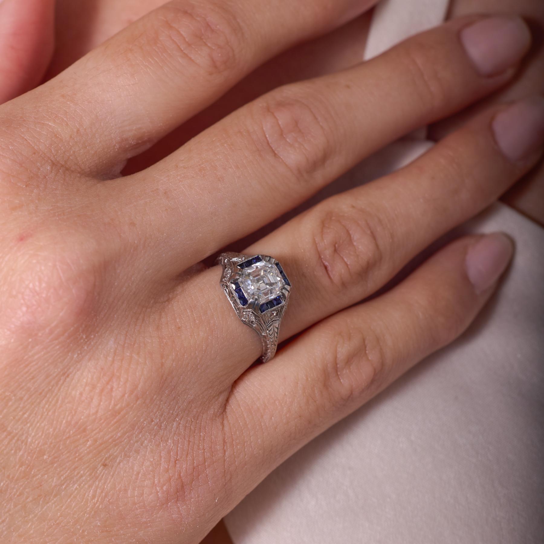 Raffinée et captivante, cette bague de fiançailles Art déco est centrée sur un spectaculaire diamant taille Asscher de 1,90 carat certifié par la GIA, dont les facettes taillées en escalier rayonnent d'une brillance glacée et d'une clarté
