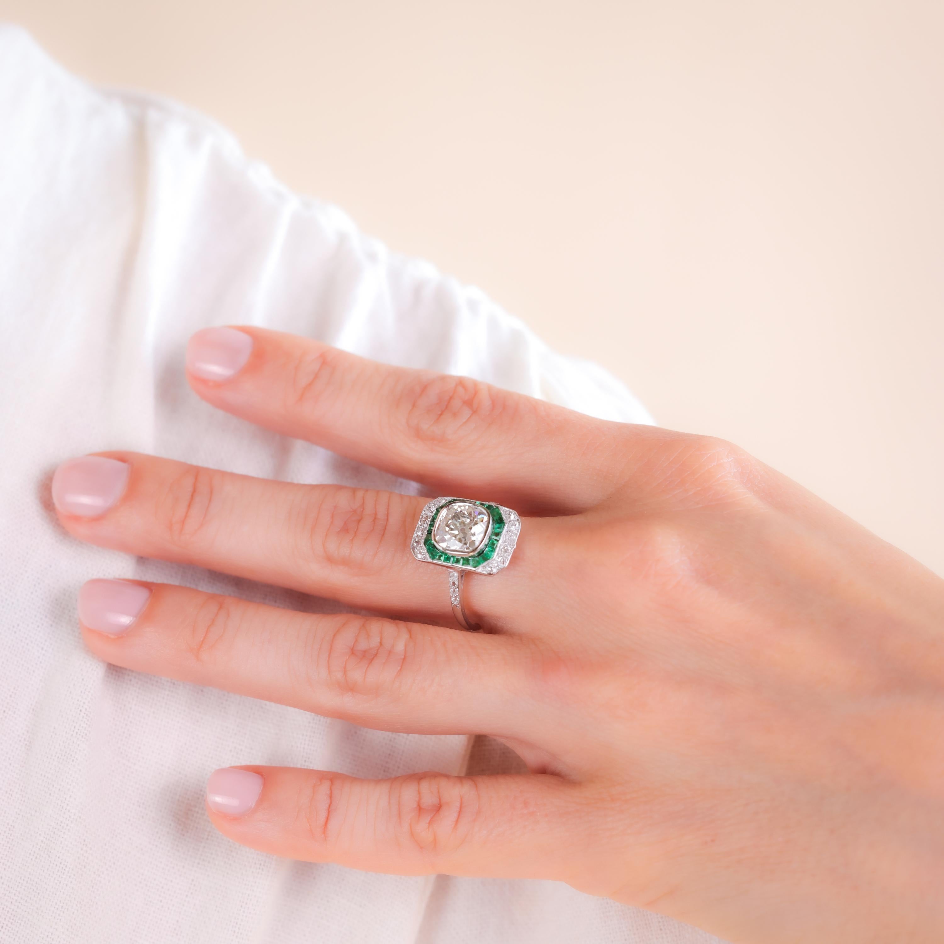Certificate: GIA #5234283574
Center Stone: Diamond
Cut: Old Mine
Weight: 2.11 Carats
Color: K
Clarity: SI2
Accent Stone: 24 Emeralds
Cut: Baguette
Weight: Approximately 0.3 Carats
Color: Green
Accent Stone: 20 Diamonds
Cut: Old Cut
Weight: