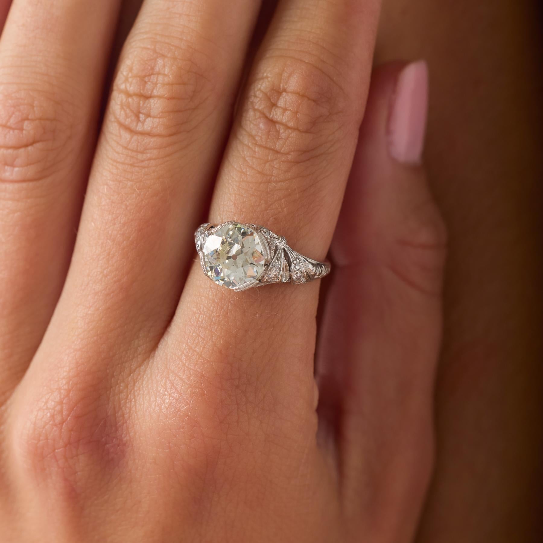 Dieser Verlobungsring im Art-Déco-Stil verkörpert die raffinierte Geometrie und strahlende Eleganz der 1930er Jahre. Im Mittelpunkt steht ein leuchtender 2,26-karätiger Diamant im alten europäischen Schliff, dessen größere Facetten ein tiefes