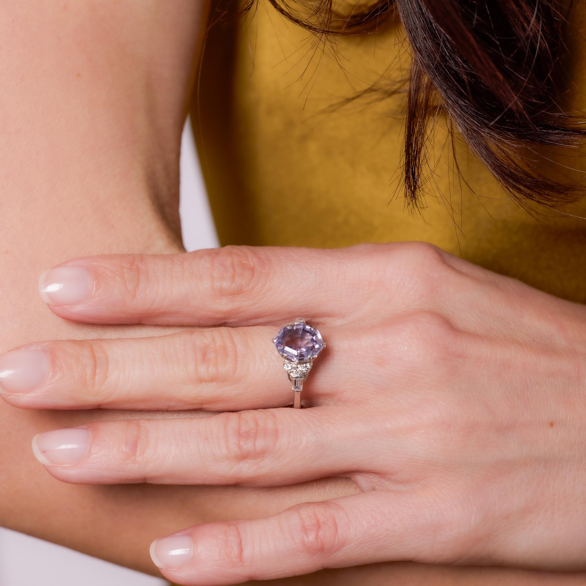Crafted in the 1930s, this Art Deco platinum ring showcases a GIA-certified 3.87-carat octagonal cut pinkish purple sapphire from Ceylon, treated with heat to enhance its vibrant hue. It is accented by two baguette and six round brilliant cut