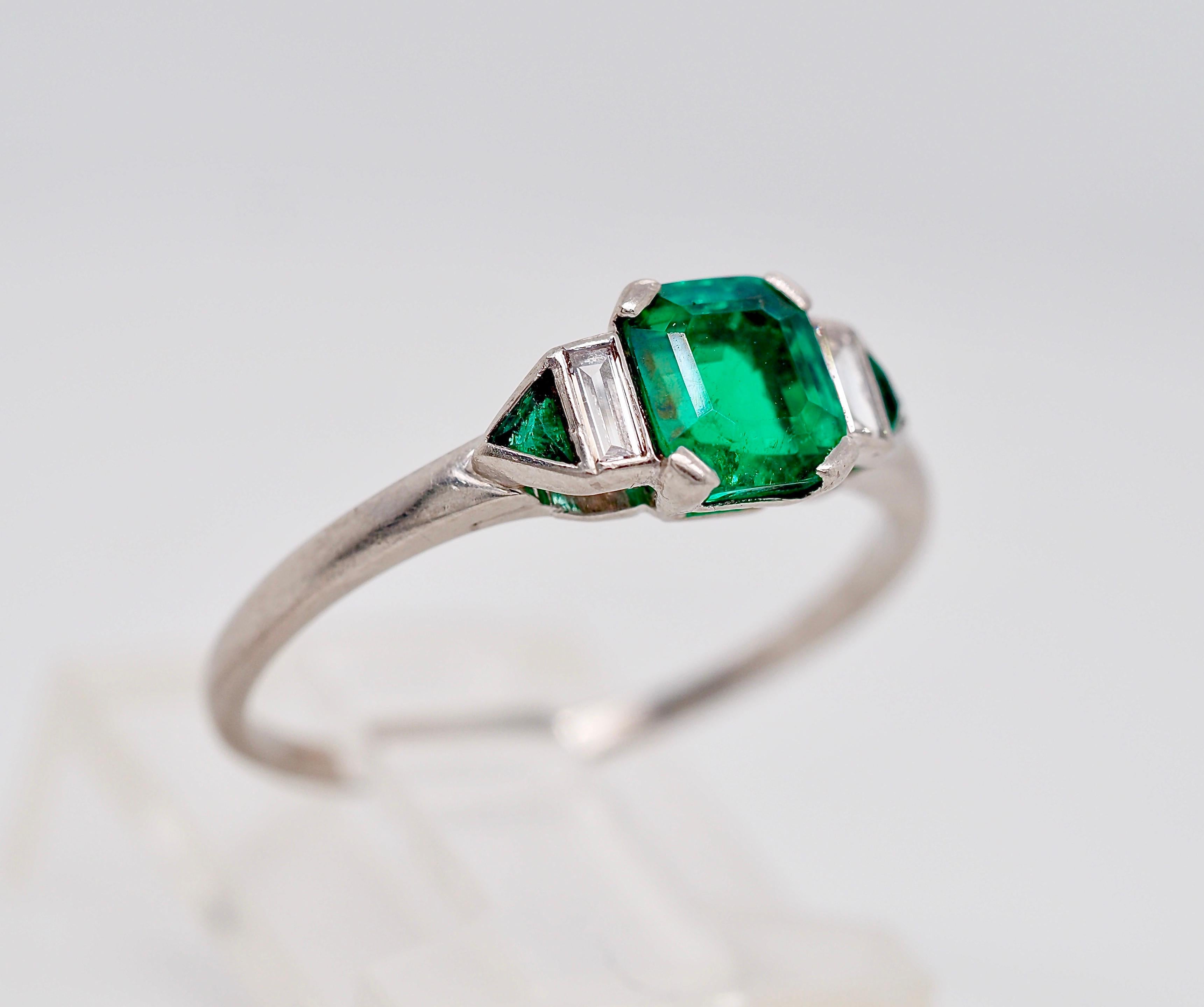 This ring is an excellent example of an Art Deco era engagement ring crafted in platinum! The lively green emerald center is a certified GIA 